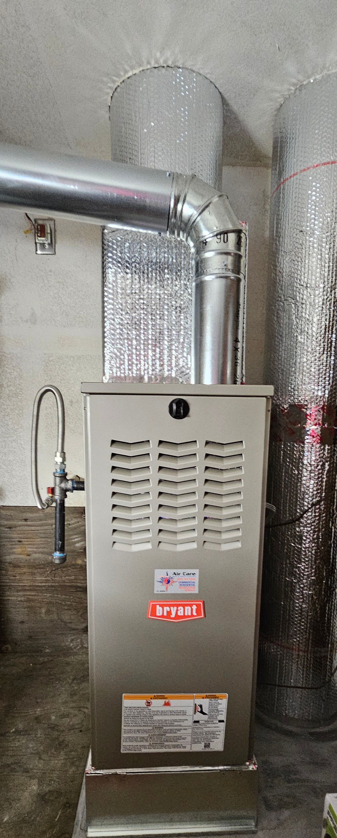 Stainless steel furnace with vent pipe in a basement or utility room near a concrete wall