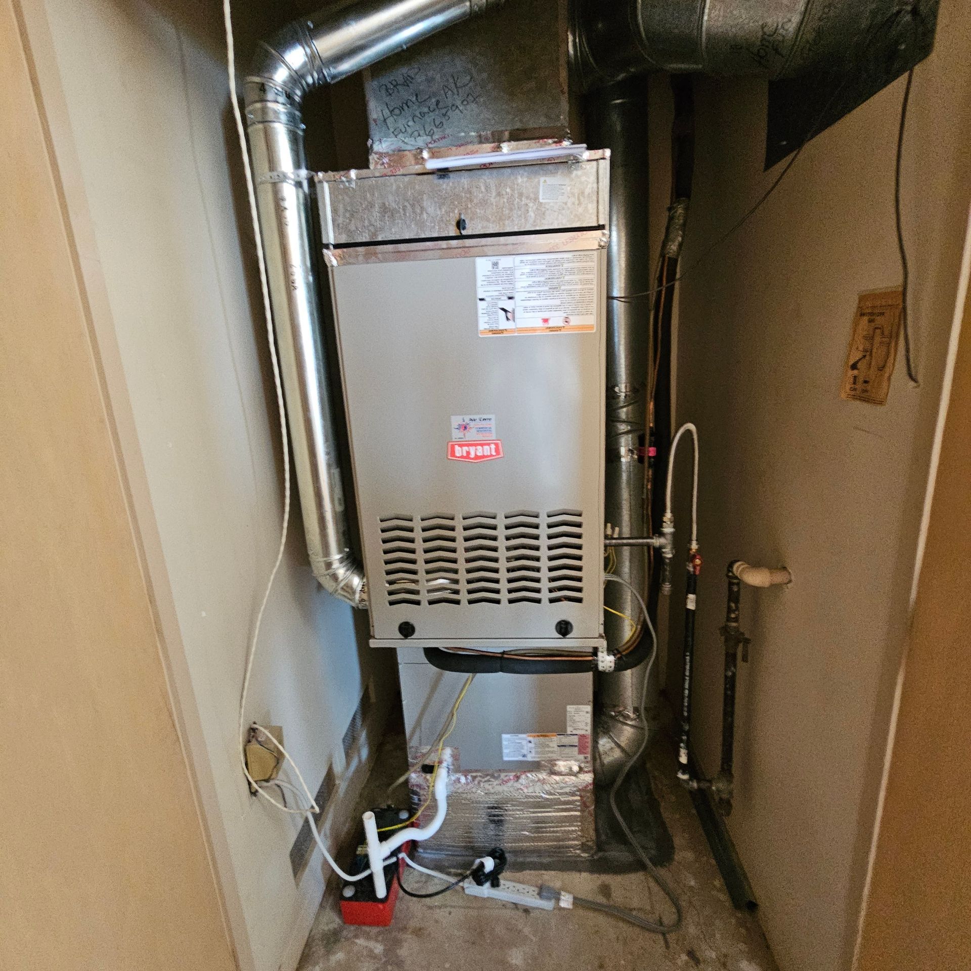 Lennox furnace in a narrow utility closet with exposed ducts and piping
