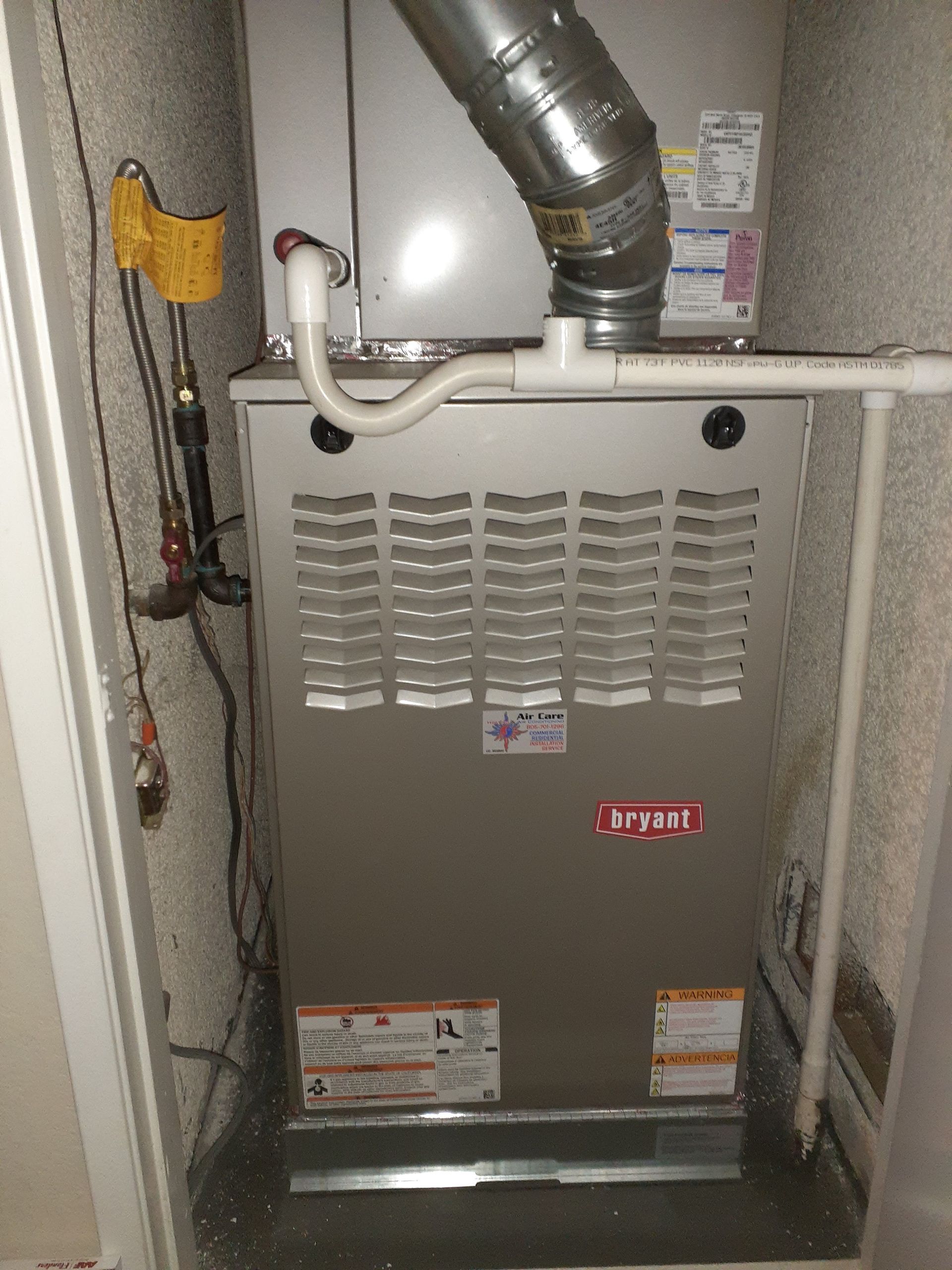 Basement furnace unit with metal vent piping and access panels in a utility closet