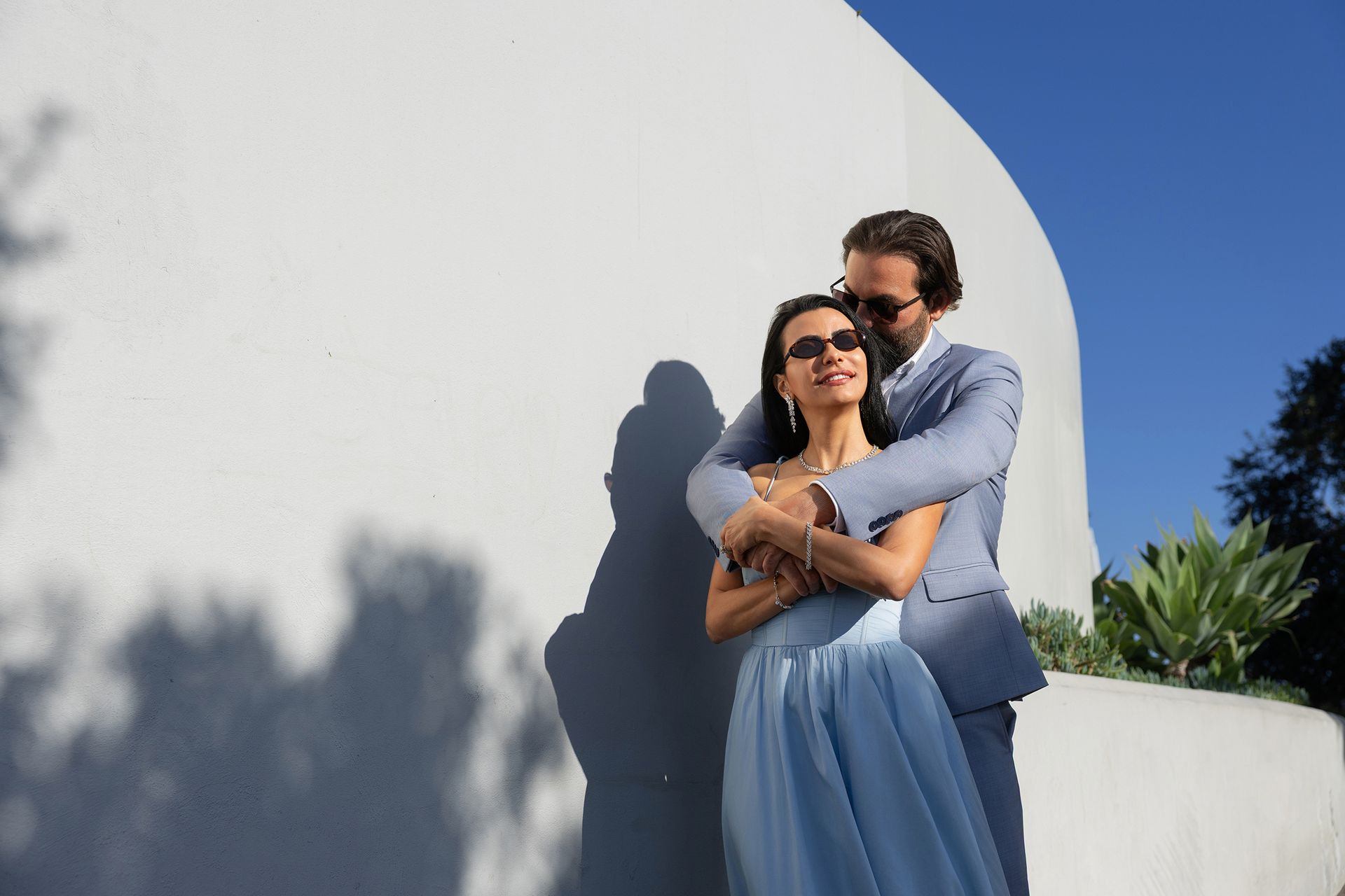 A man in a suit is hugging a woman in a blue dress.