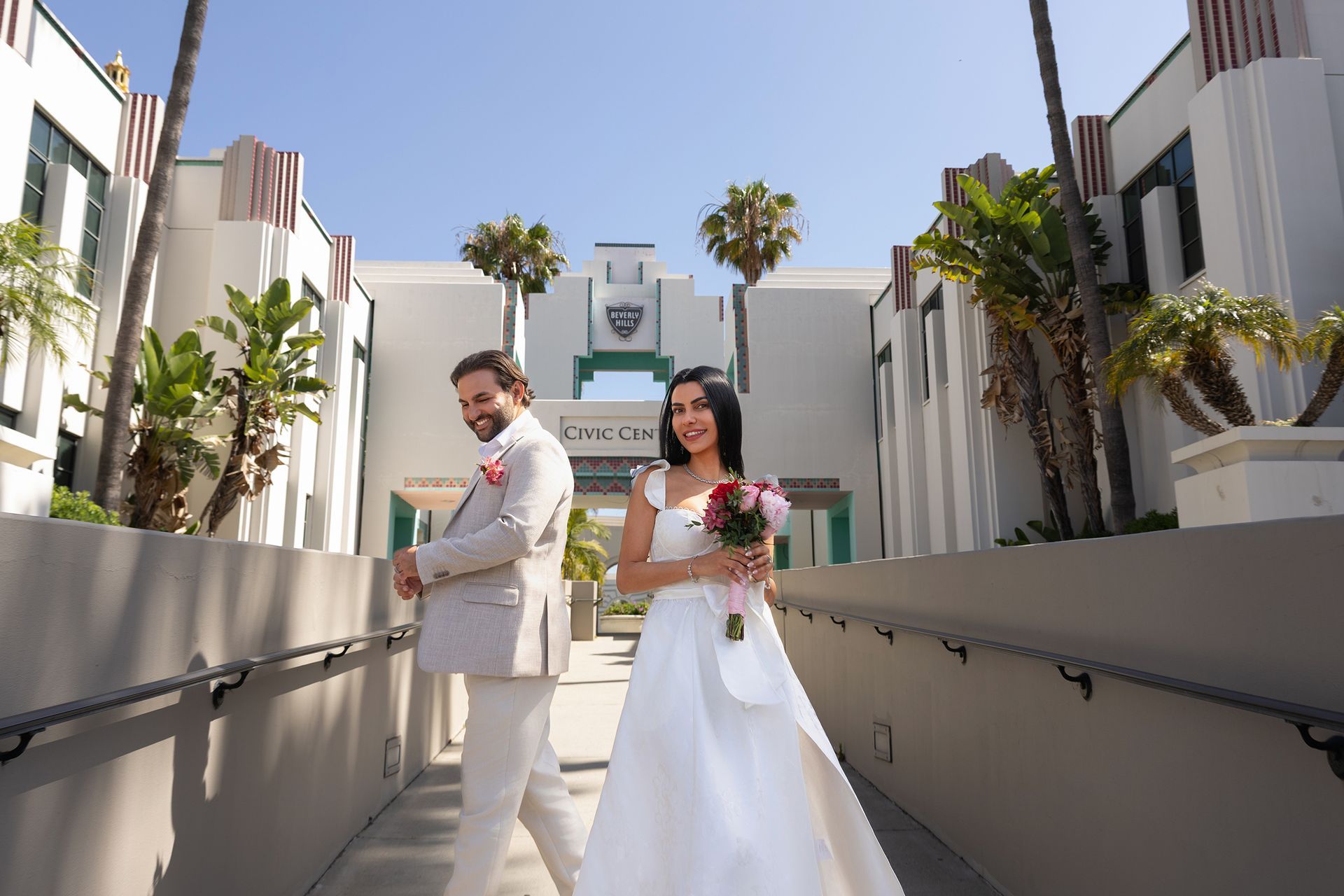 A bride and groom are walking down a ramp in front of a building.