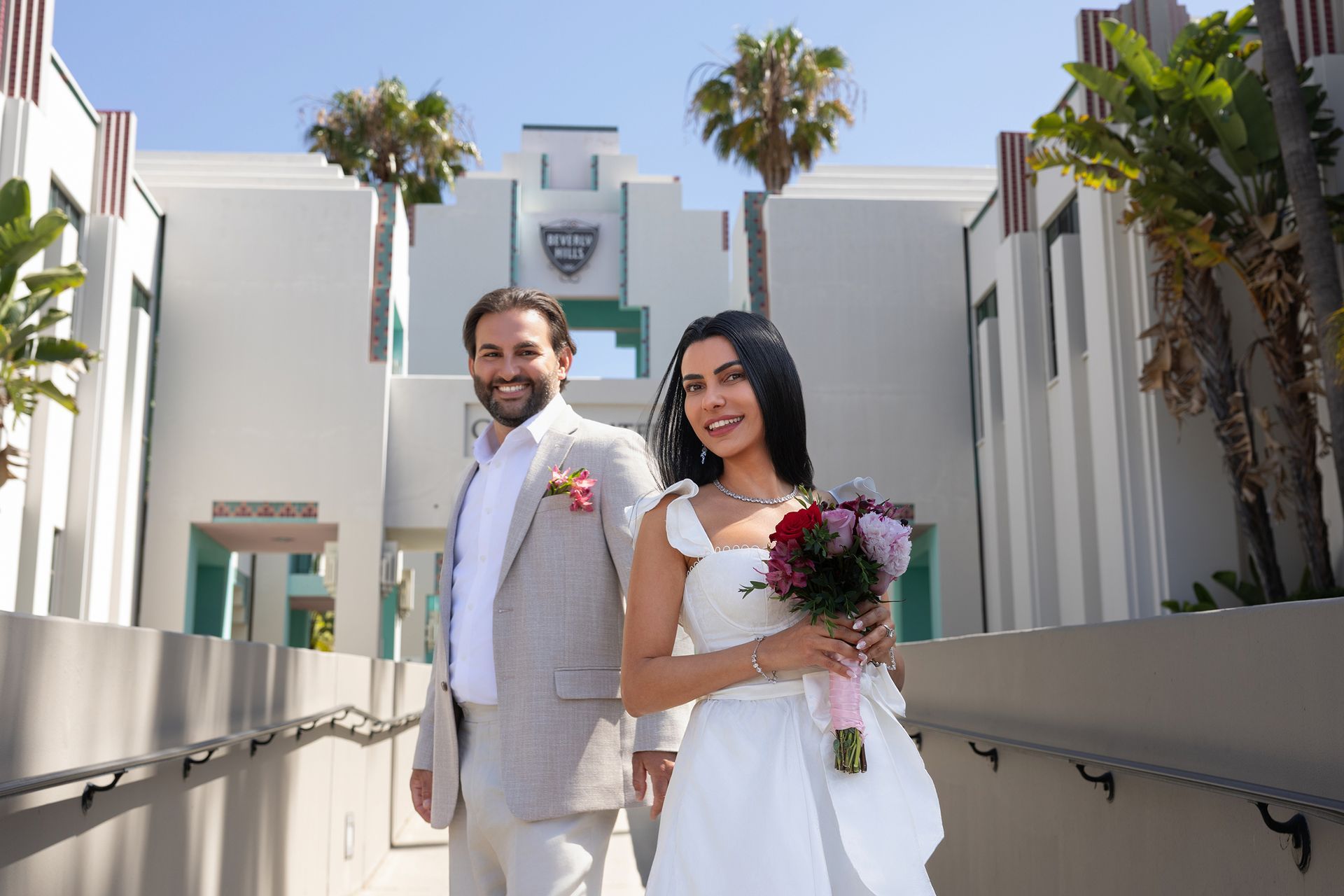 A bride and groom are posing for a picture in front of a building.