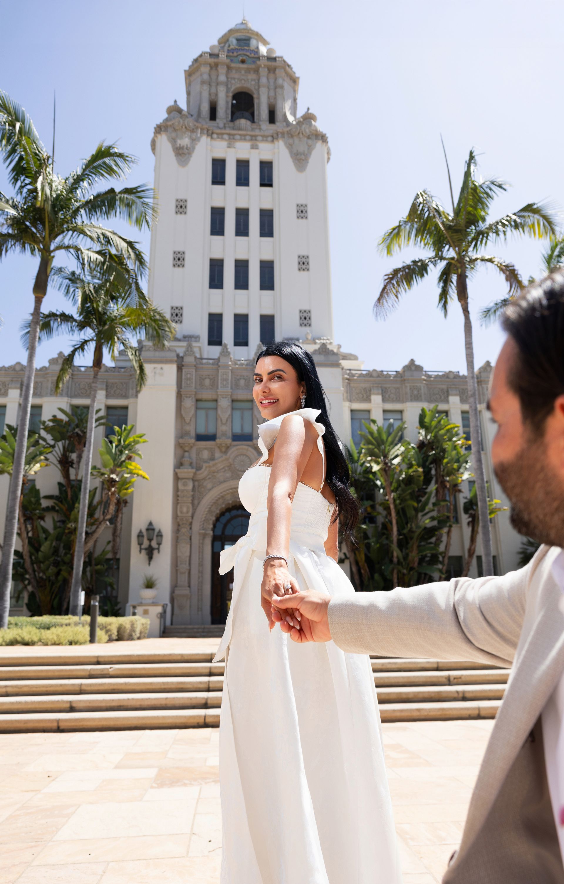 A bride and groom are holding hands in front of a large white building.