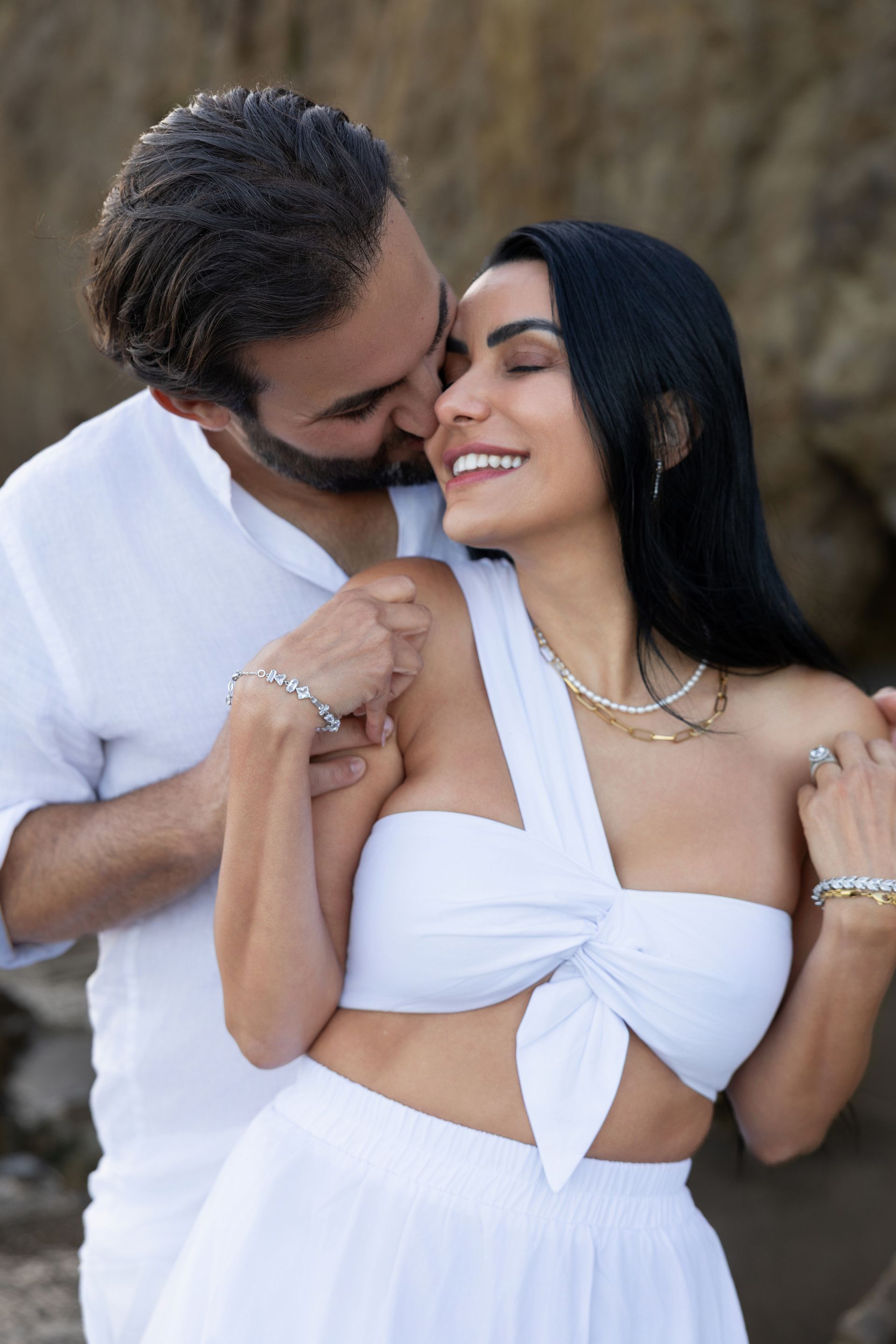 A man is kissing a woman on the cheek on the beach.