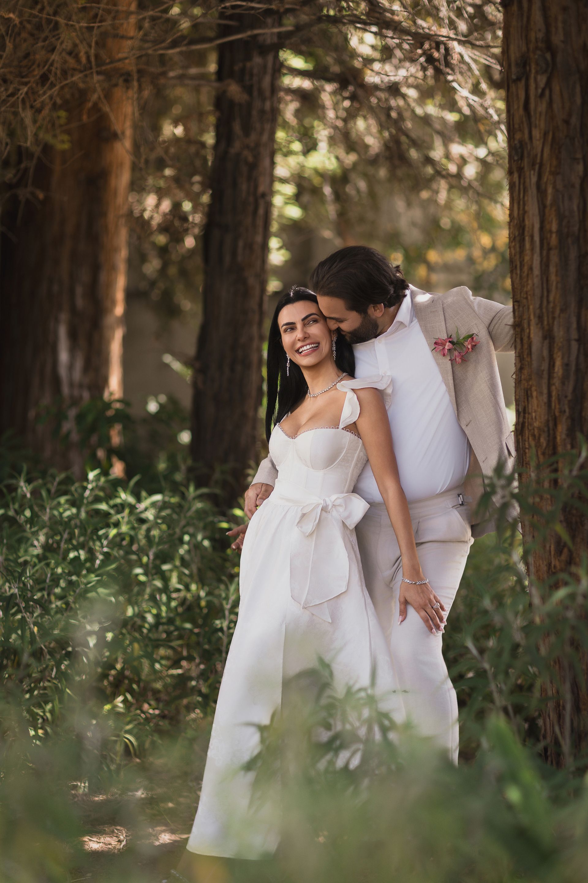 A bride and groom are posing for a picture in the woods.
