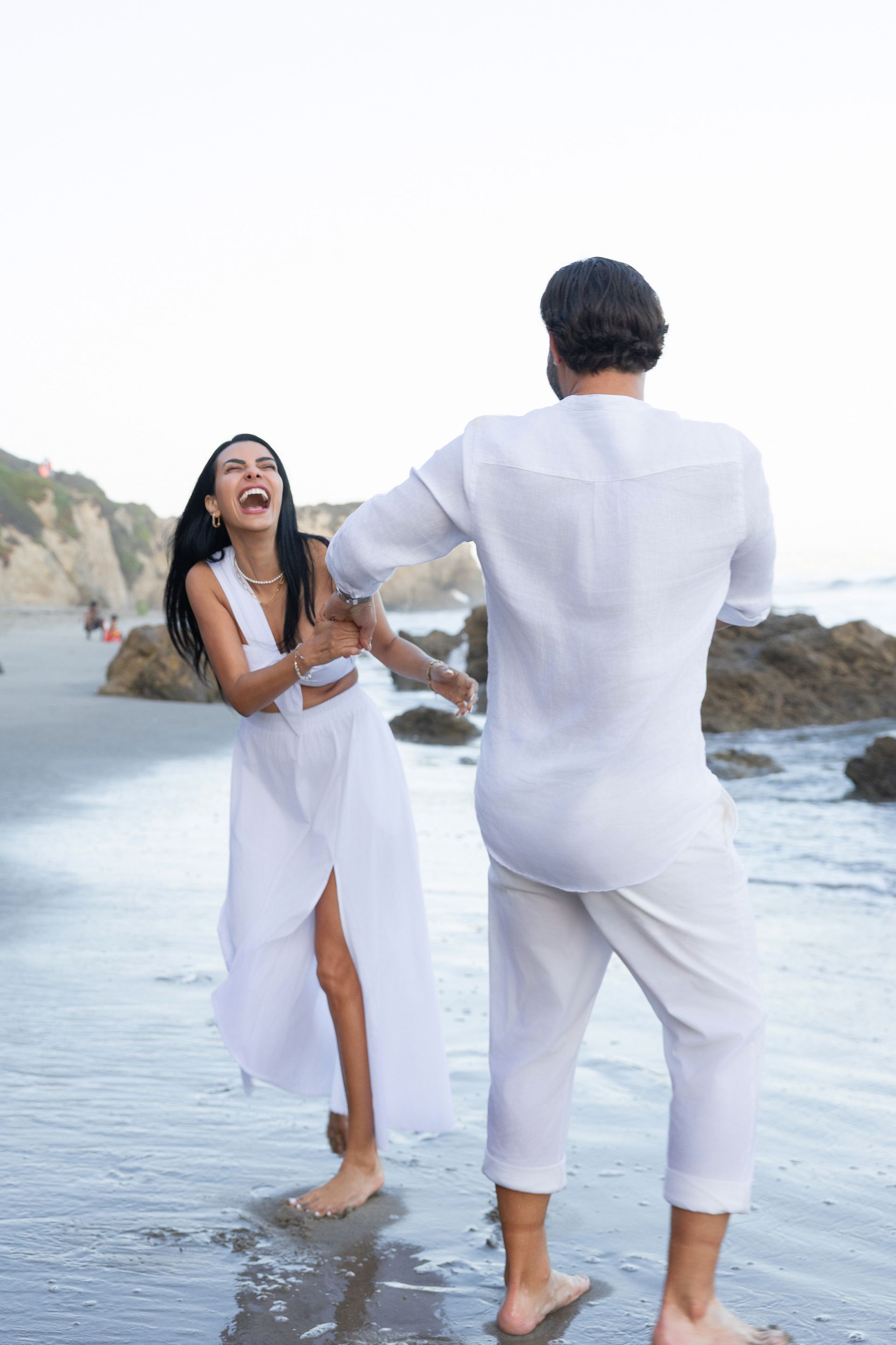 A man and a woman are dancing on the beach.