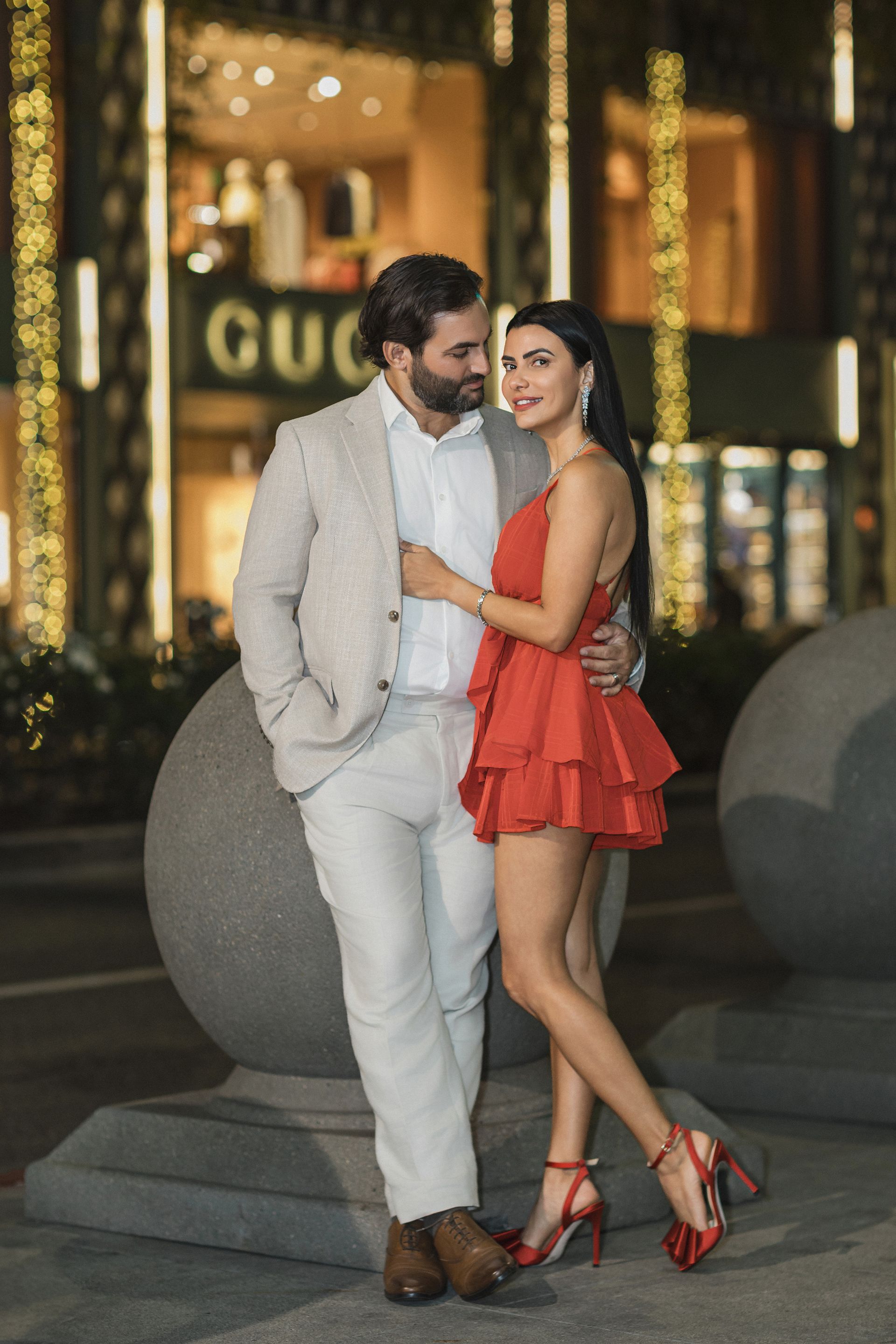 A man and a woman are standing next to each other in front of a gucci store.