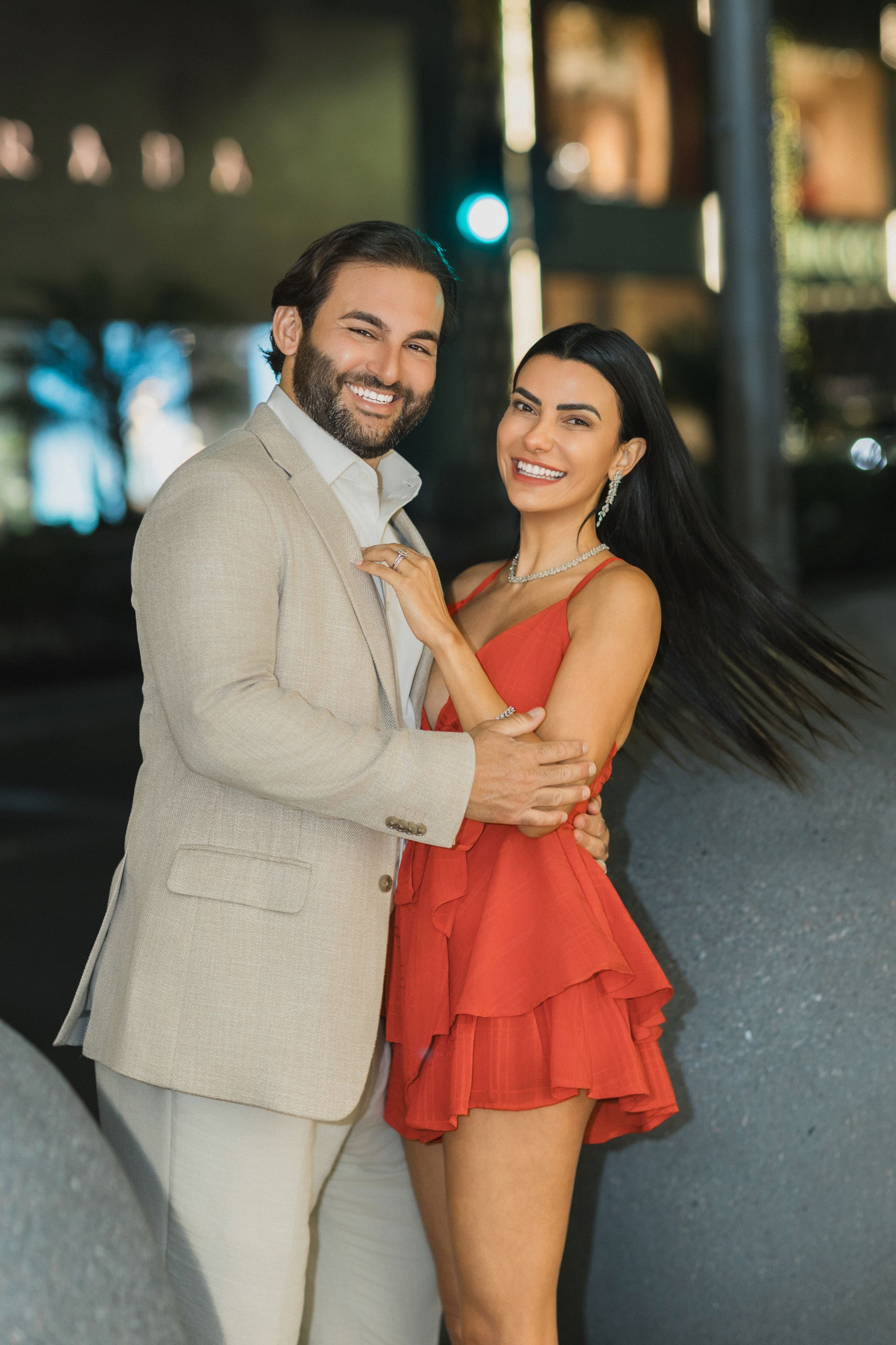 A man in a suit and a woman in a red dress are posing for a picture.