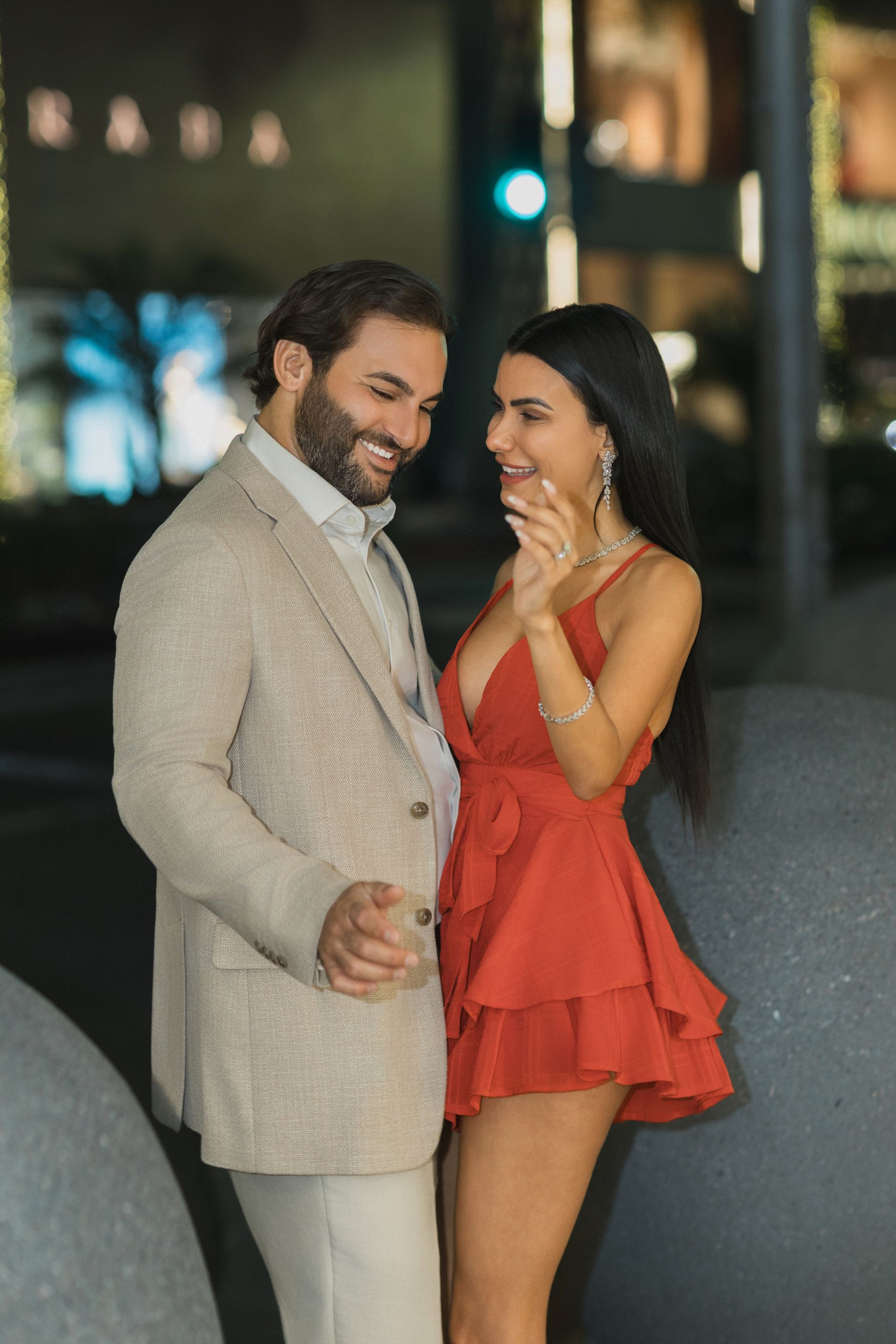 A man in a suit and a woman in a red dress are standing next to each other.