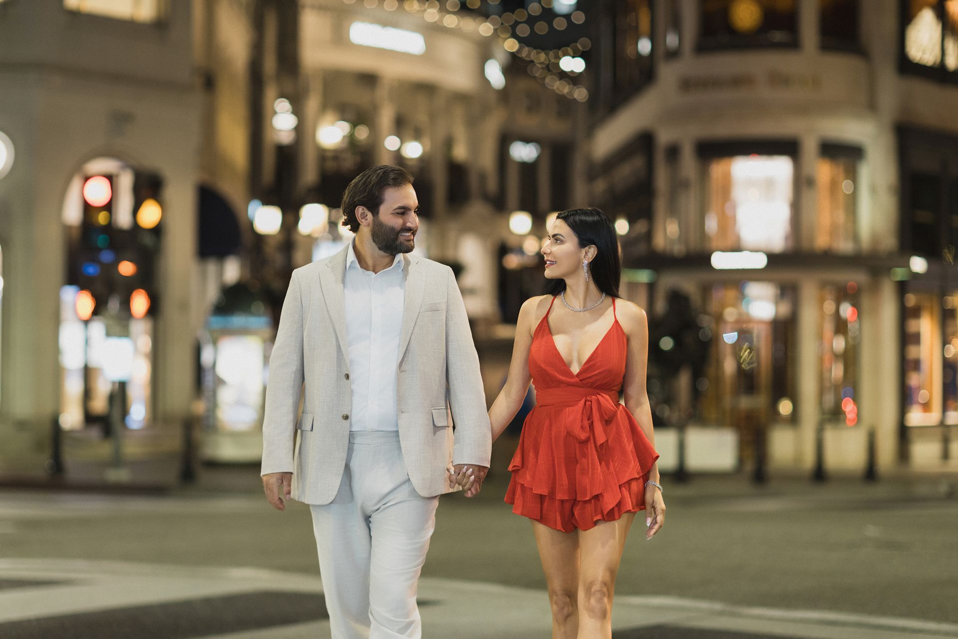 A man and a woman are walking down the street holding hands.