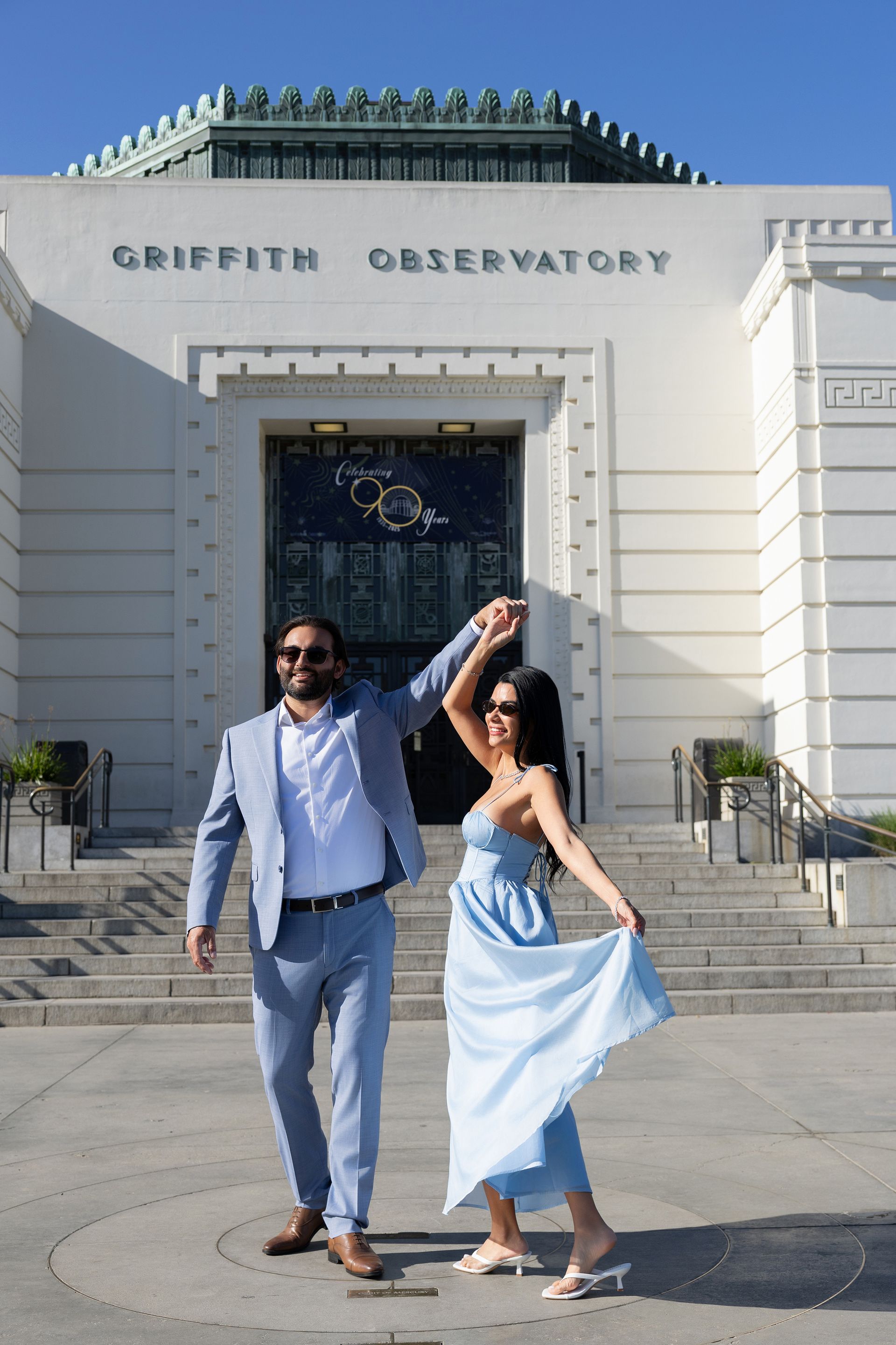 A man and a woman are dancing in front of a building.
