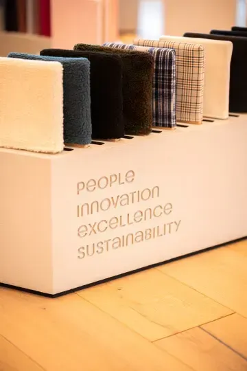 Un socle d'exposition rectangulaire blanc portant les mots « PERSONNES », « INNOVATION », « EXCELLENCE » et « DURABILITÉ ».