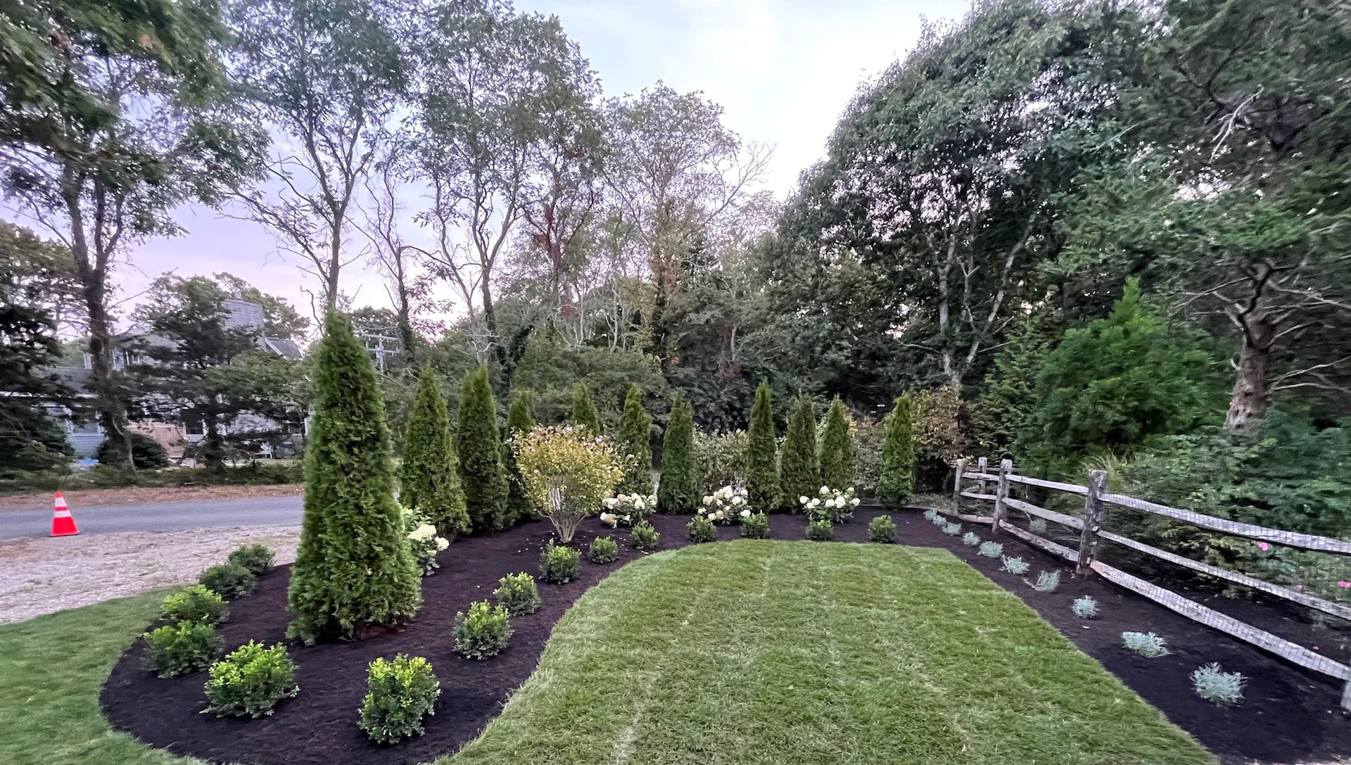 A lush green yard with a fence and trees in the background.