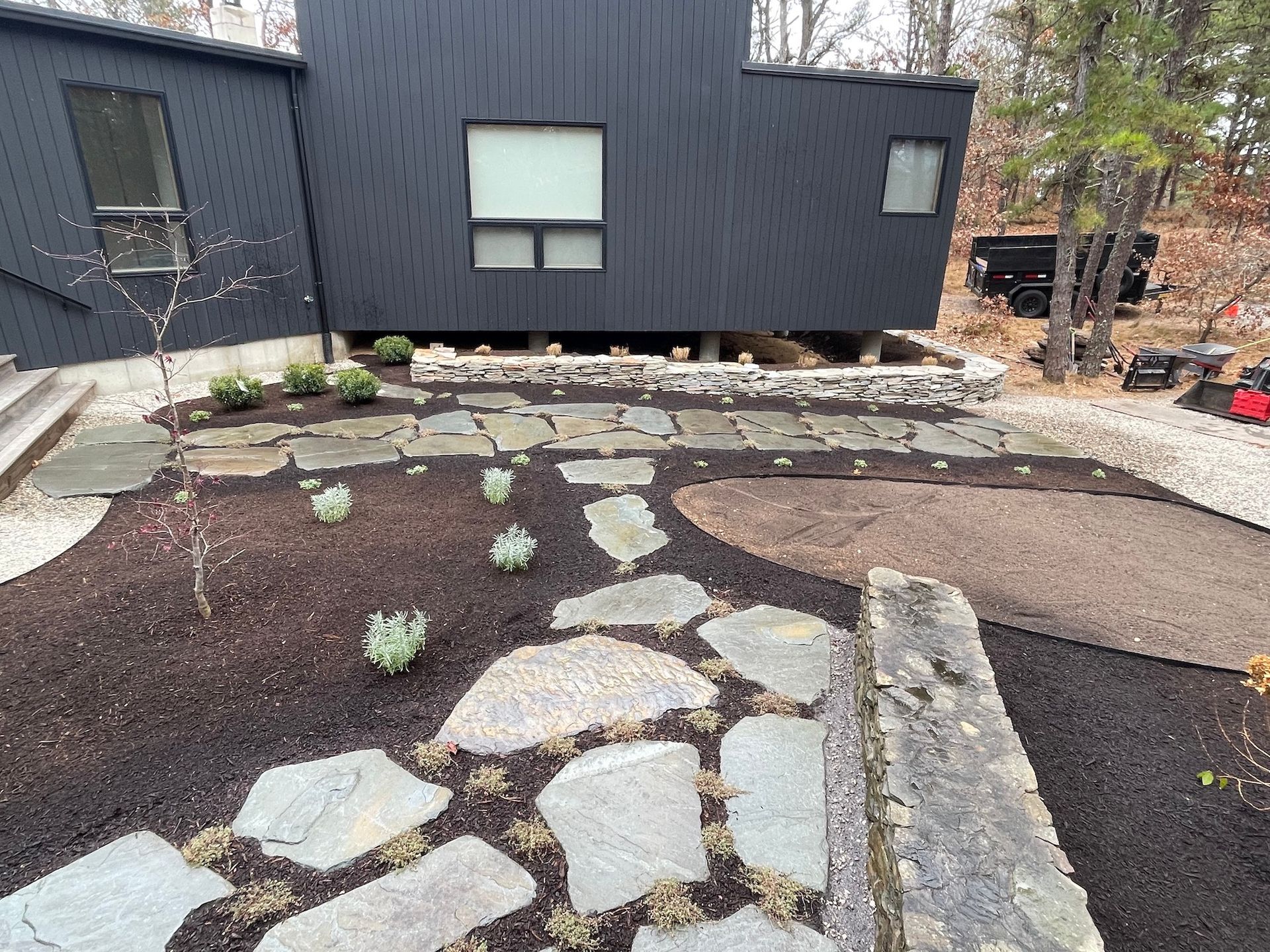 A black house with a stone walkway in front of it.