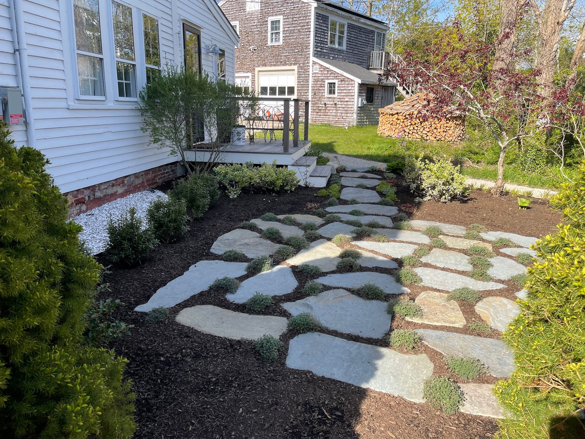A stone walkway leading to a house with a porch.