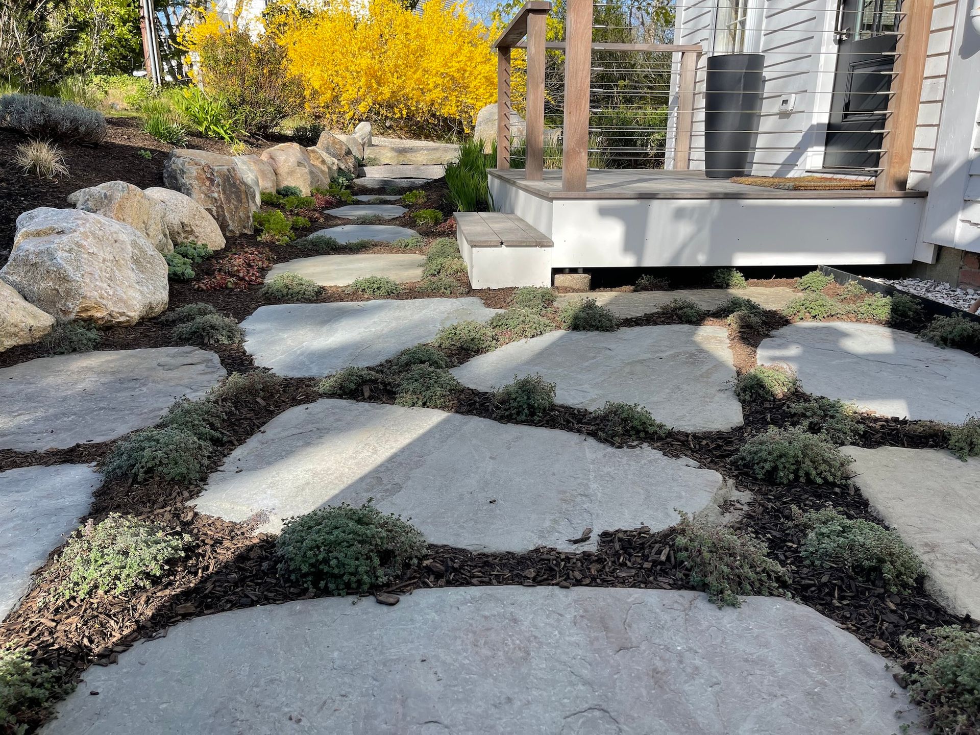 A stone walkway leading to a house with a deck