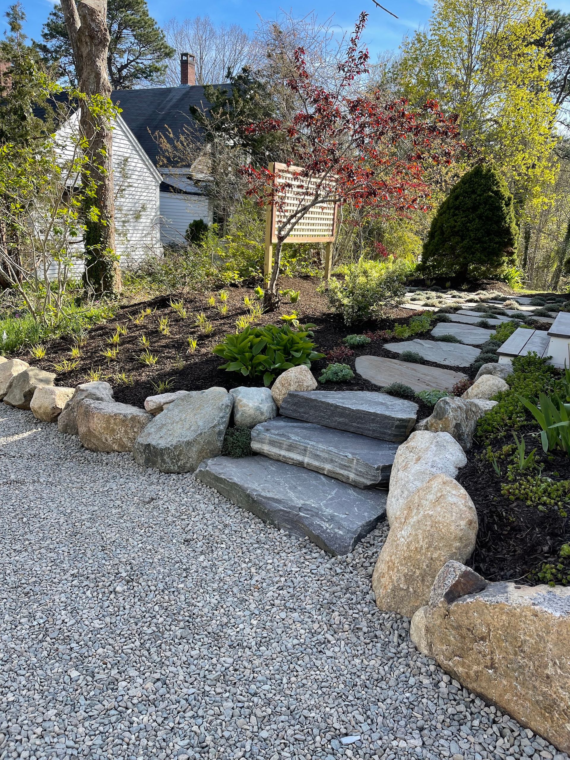 A stone walkway leading to a house in a garden.