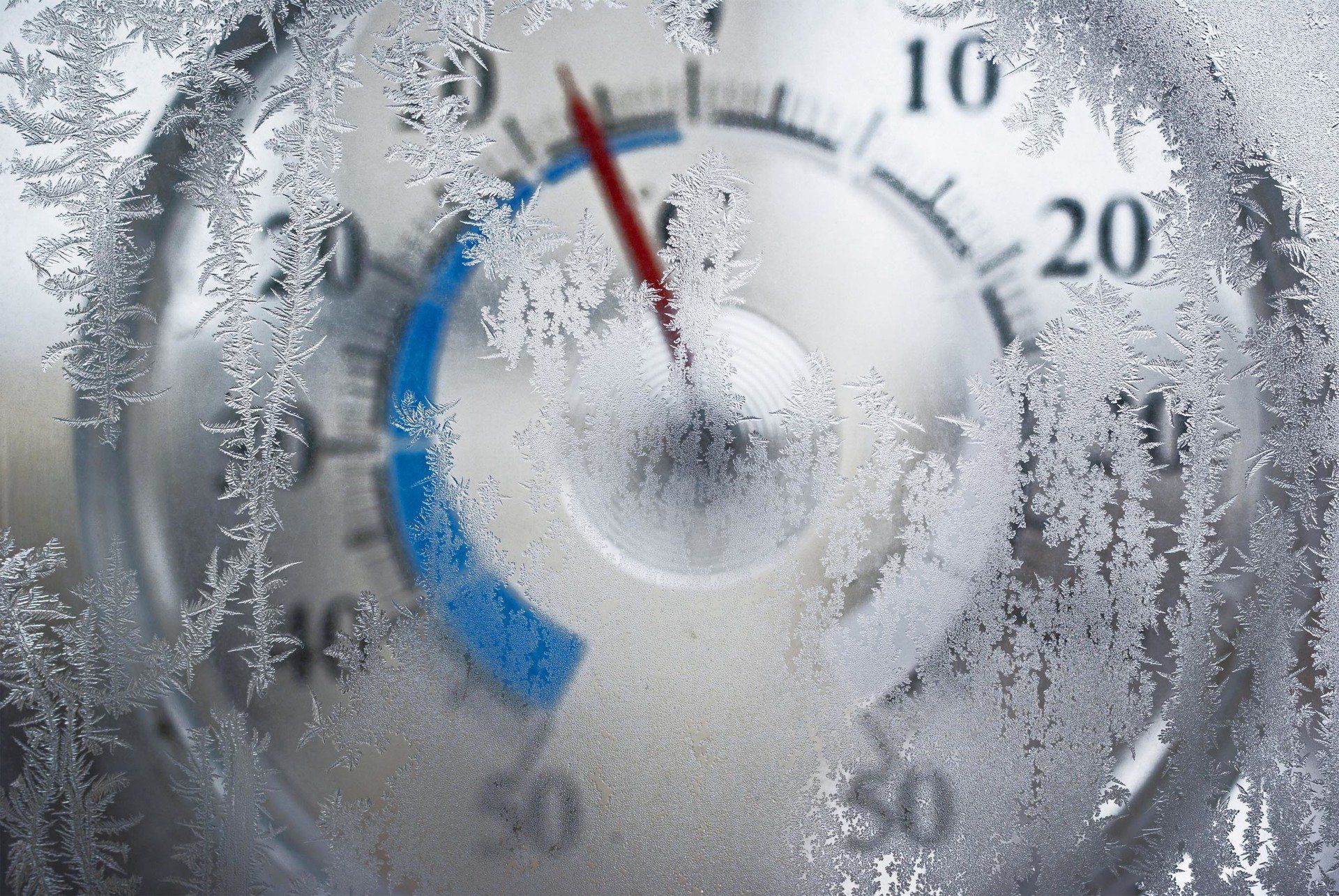 Termometro attraverso una finestra ghiacciata, che indica una temperatura fredda sotto lo zero.