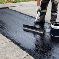 Sealer bucket being applied to pavement