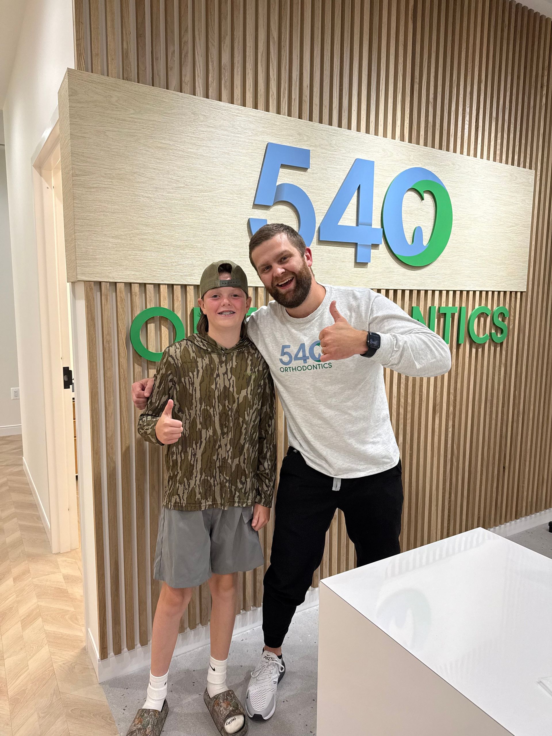 540 Orthodontics reception desk with wood slat wall, white counters, and soft LED lighting