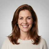 Smiling woman with shoulder-length brown hair wearing a cream sweater against a light gray background