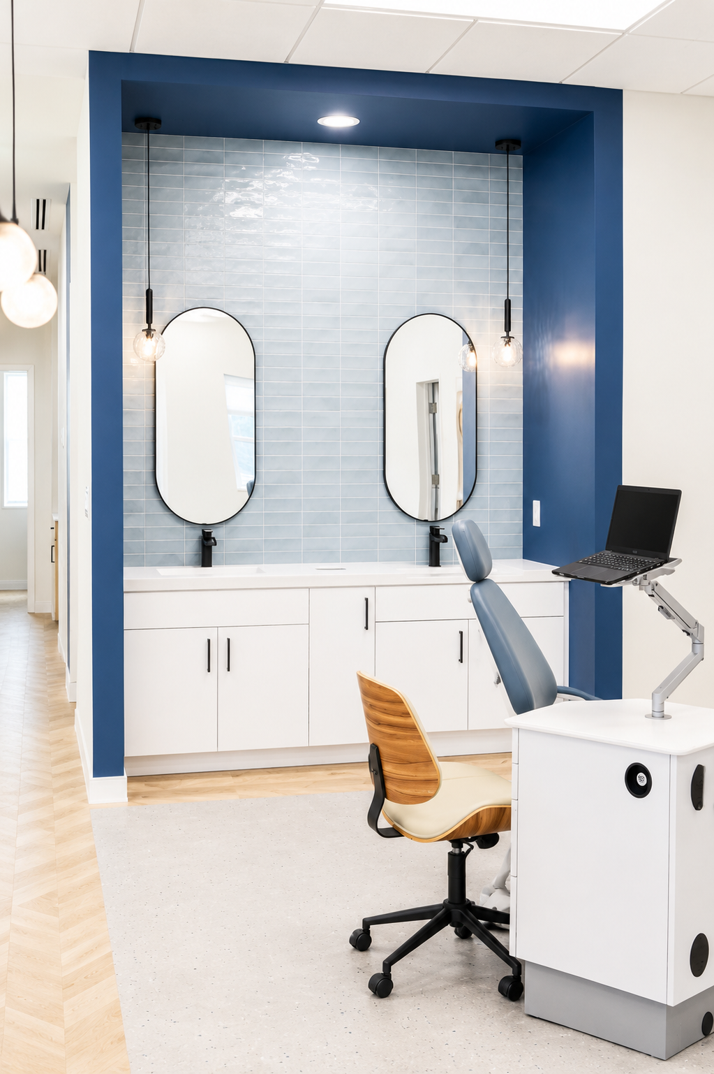 Modern dental exam room with chair, overhead light, cabinet, and blue accent wall