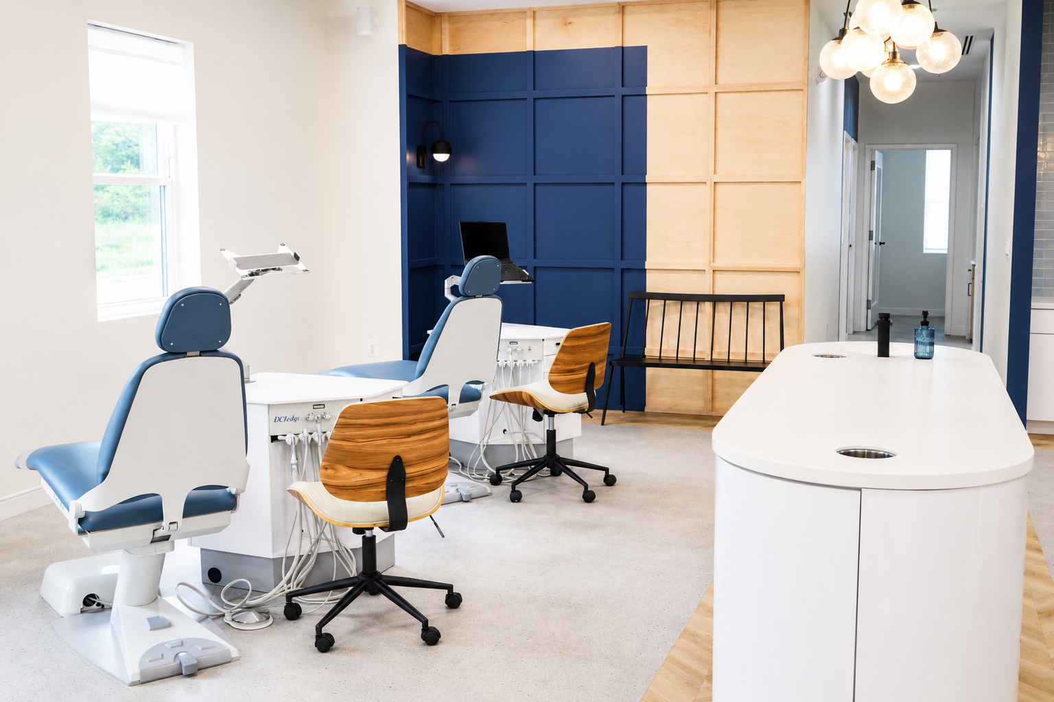 Modern dental clinic with three white chairs, blue wall panels, and a white treatment cabinet