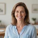 Smiling woman in a light blue shirt standing in a softly lit room