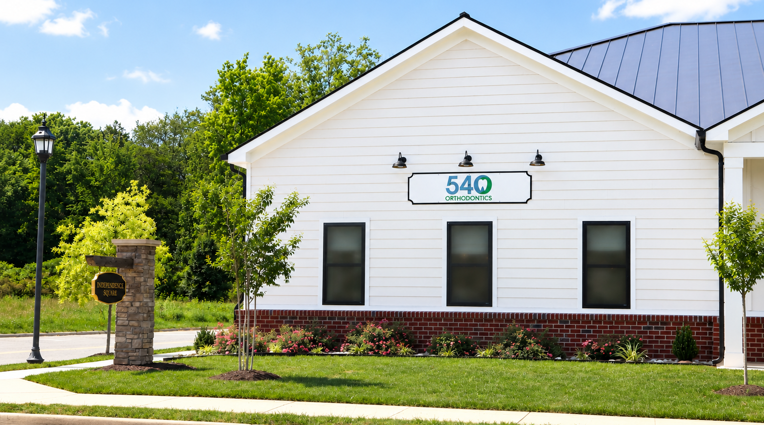 White building with green-trimmed sign reading 548, black windows, and red shrubs along the front