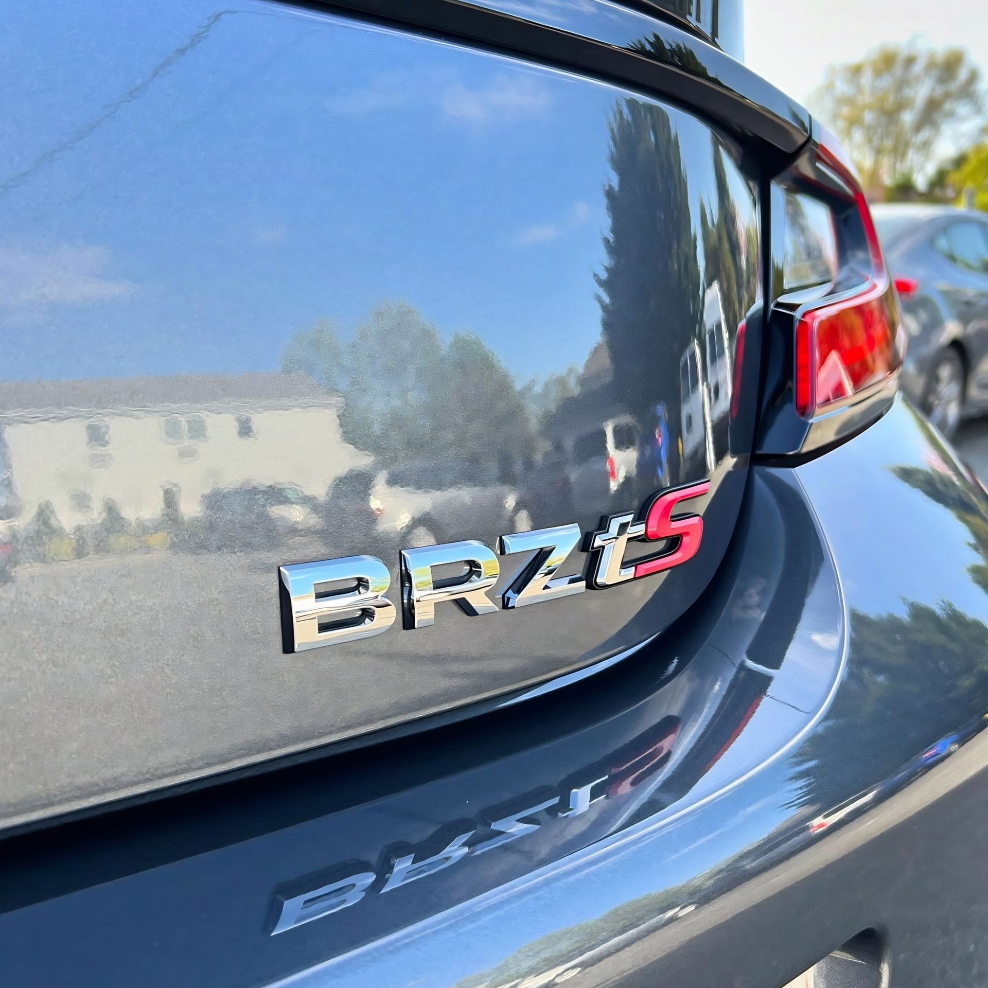 Close-up of a gray Toyota BRZ rear badge and taillight in sunlight