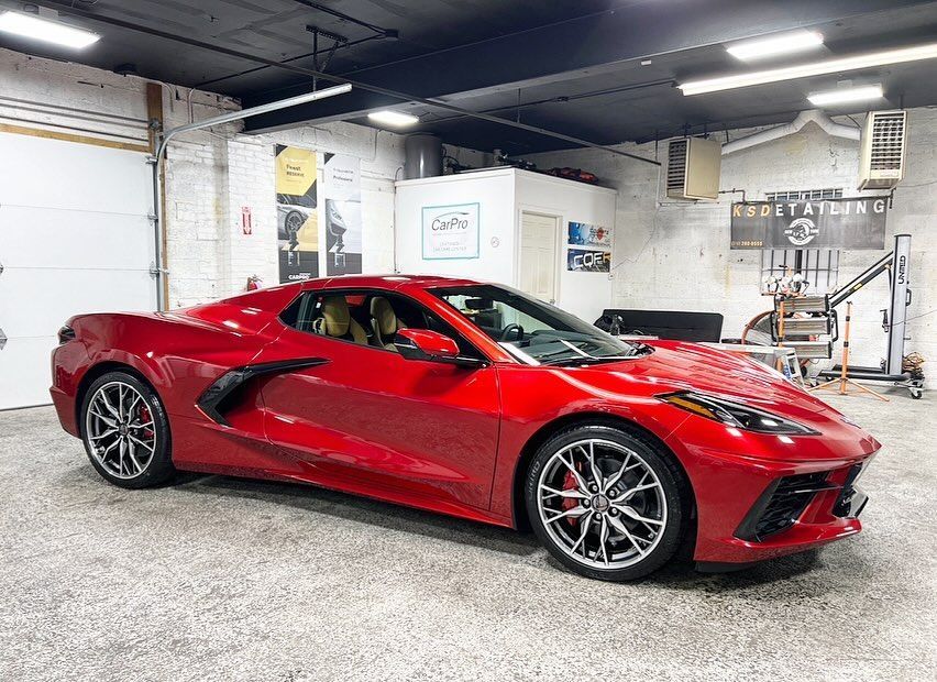 Red sports car parked inside a garage, side view.