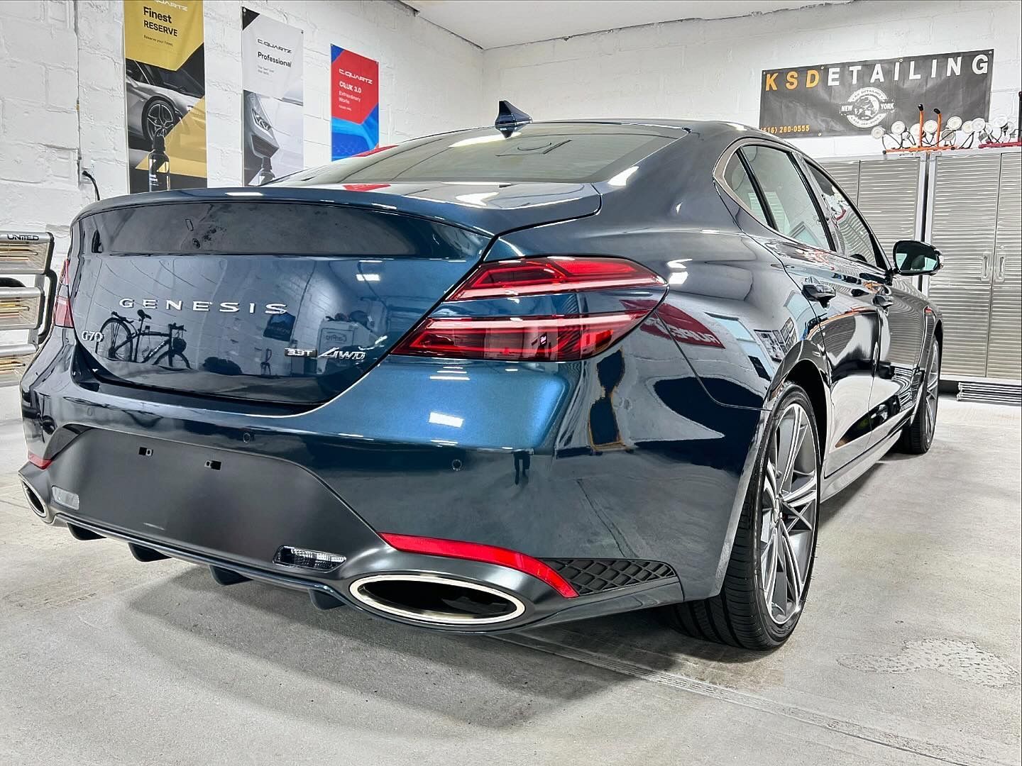 Black Mercedes sedan in an auto shop, rear view, with chrome exhaust and glossy paint