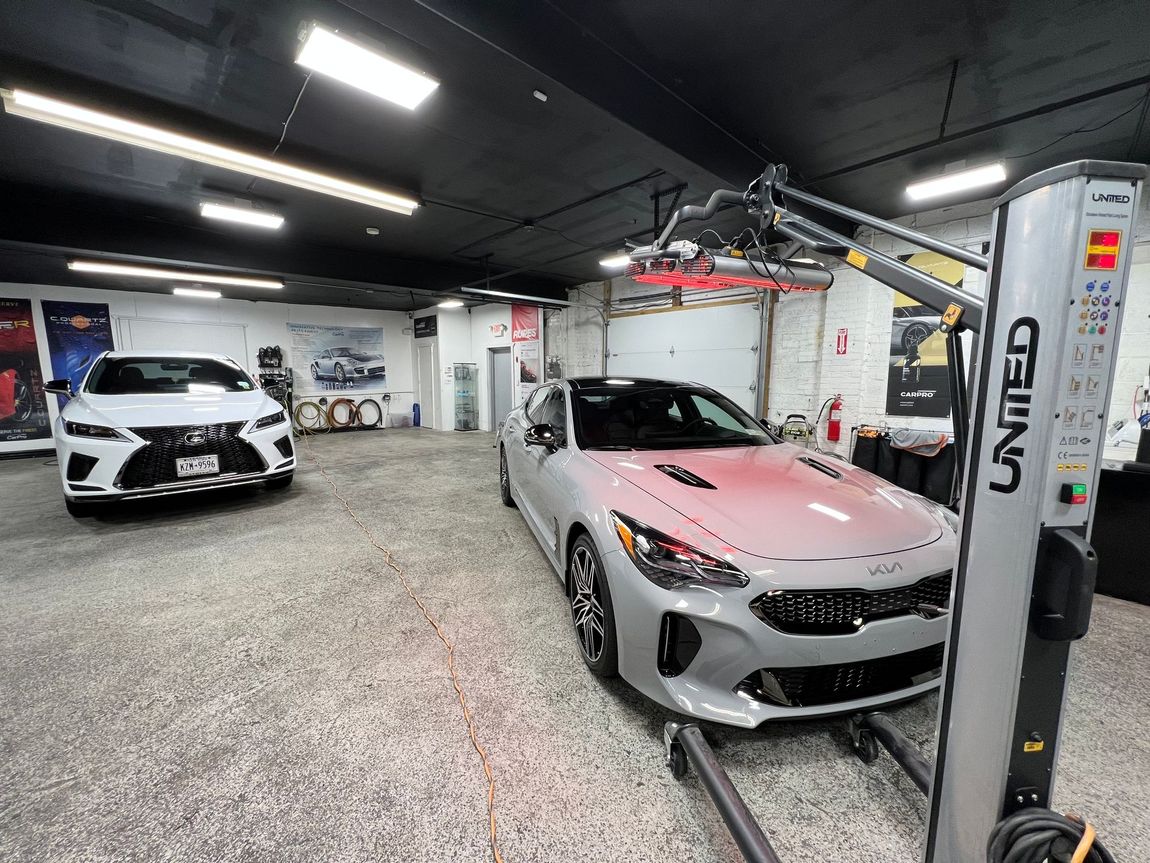 Luxury car showroom with a silver sports car under a ceiling lift and a white car in the background