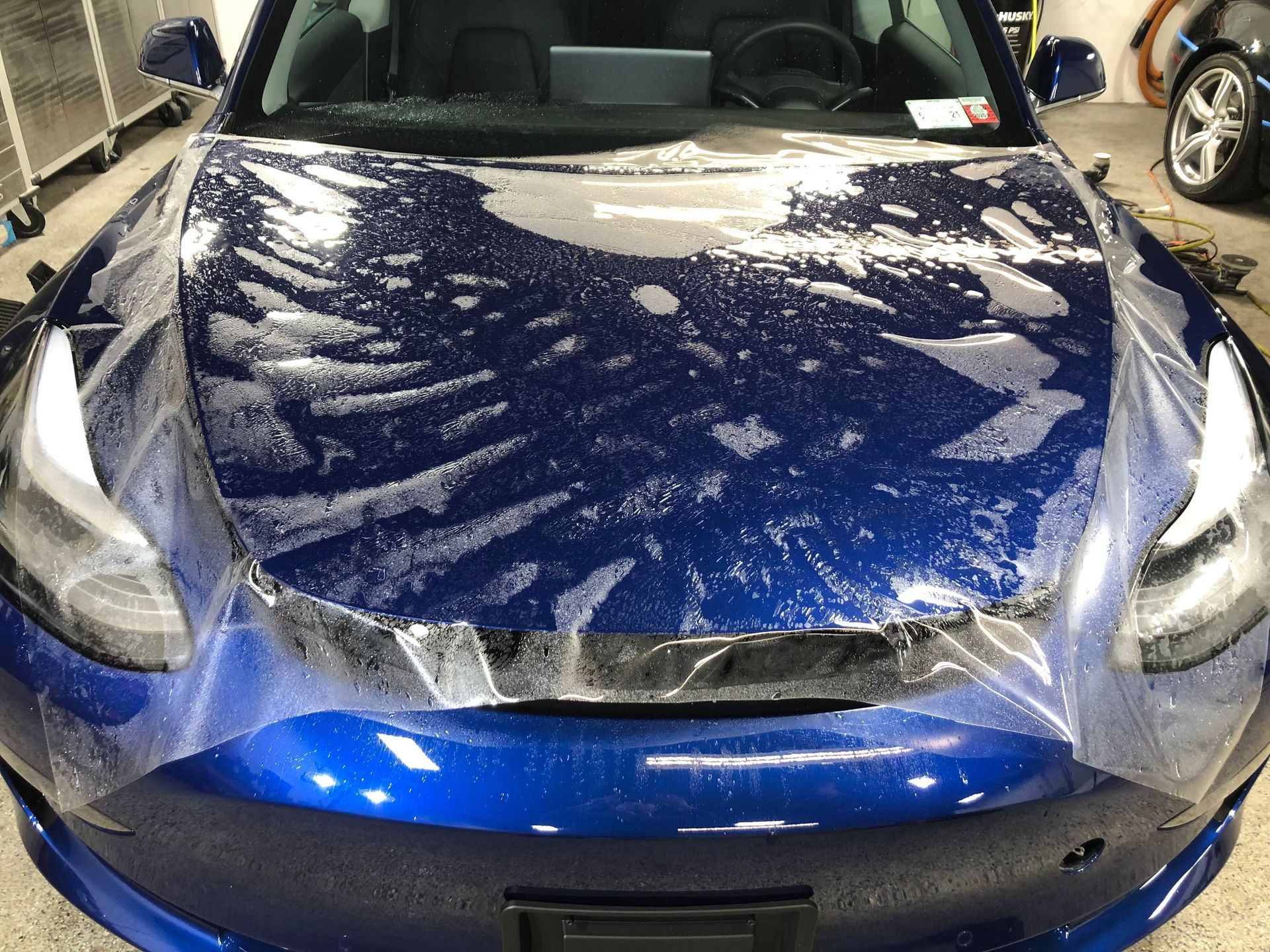 Red Tesla car displayed indoors, front view, with glossy paint and showroom lighting