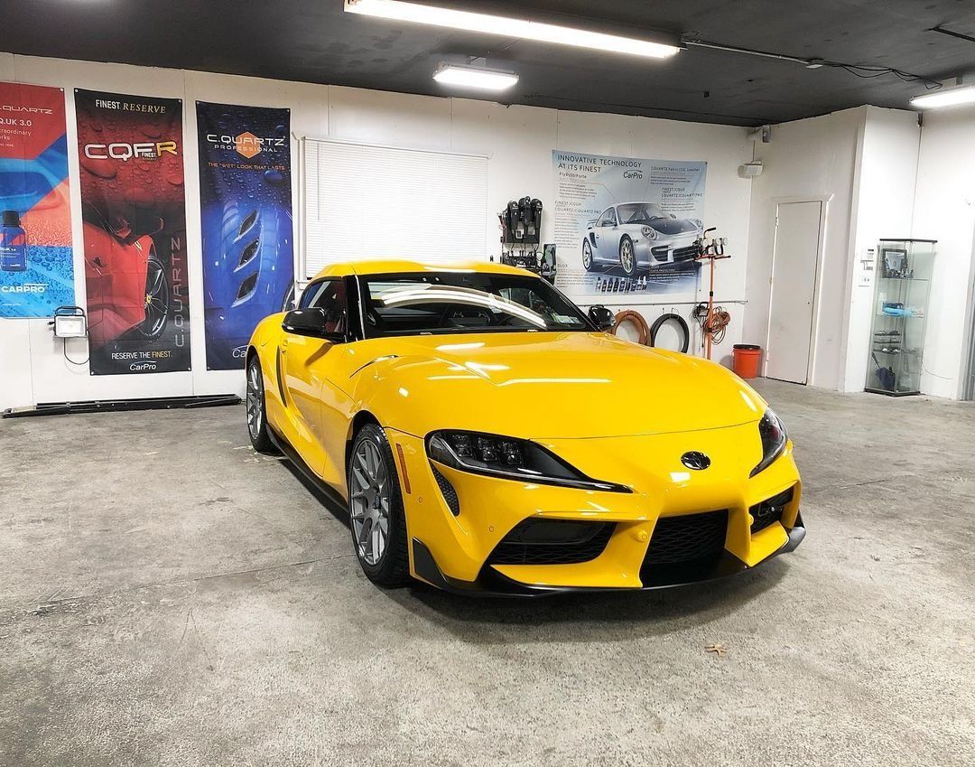 Yellow sports car in a showroom with wall posters and bright overhead lights
