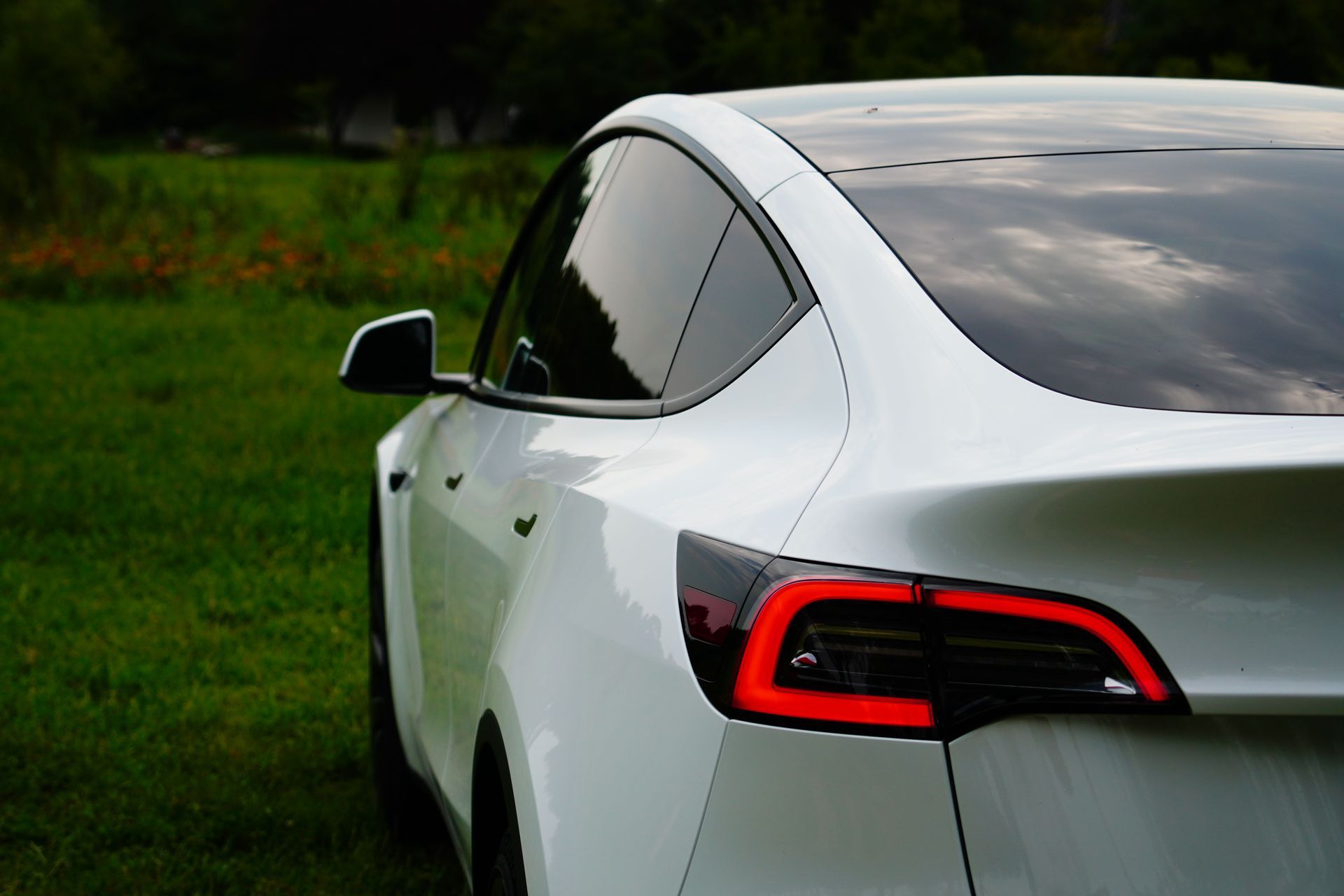 Hands applying transparent film to a red car windshield