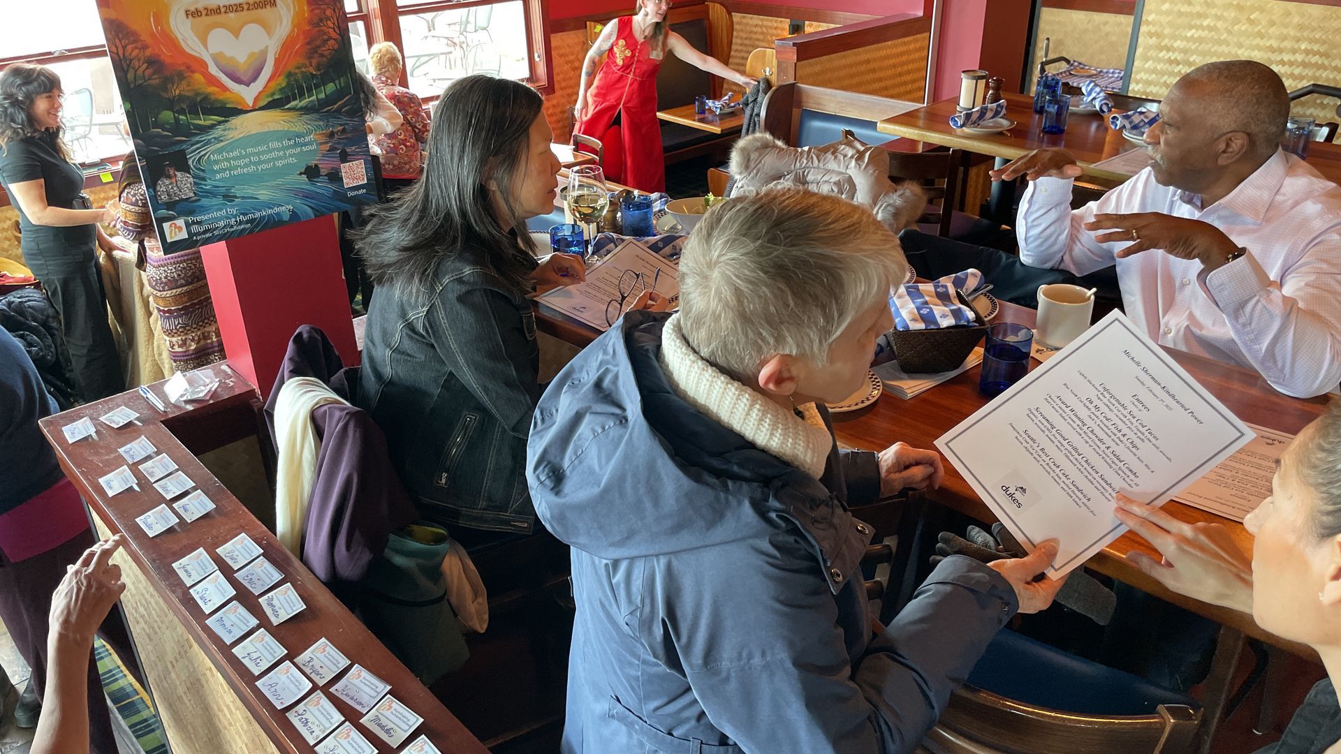 People at a table, some reviewing papers, inside a restaurant with colorful decor.