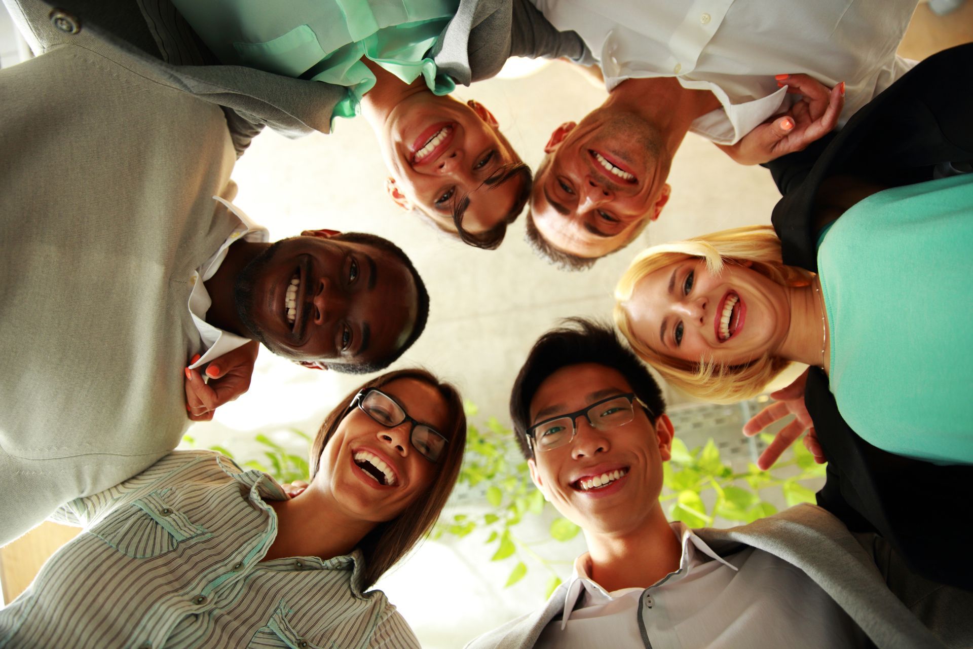 Six smiling people looking down, forming a circle.