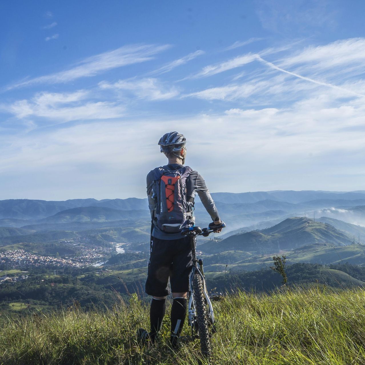 Read Full Letter of Comment Mountain biker stands with bike, looking out at a scenic valley under a blue sky.