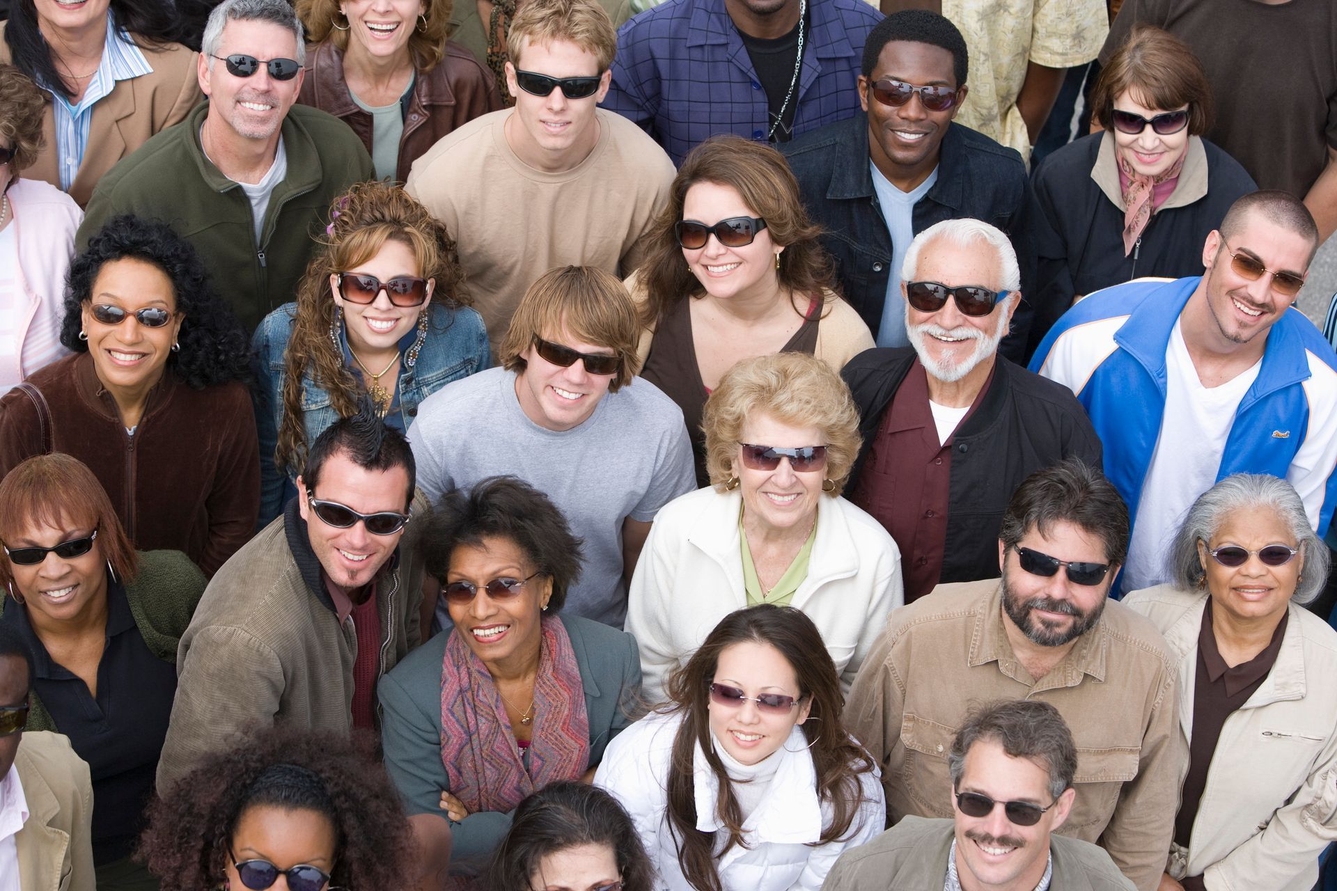 Group of people wearing sunglasses, looking upwards and smiling.