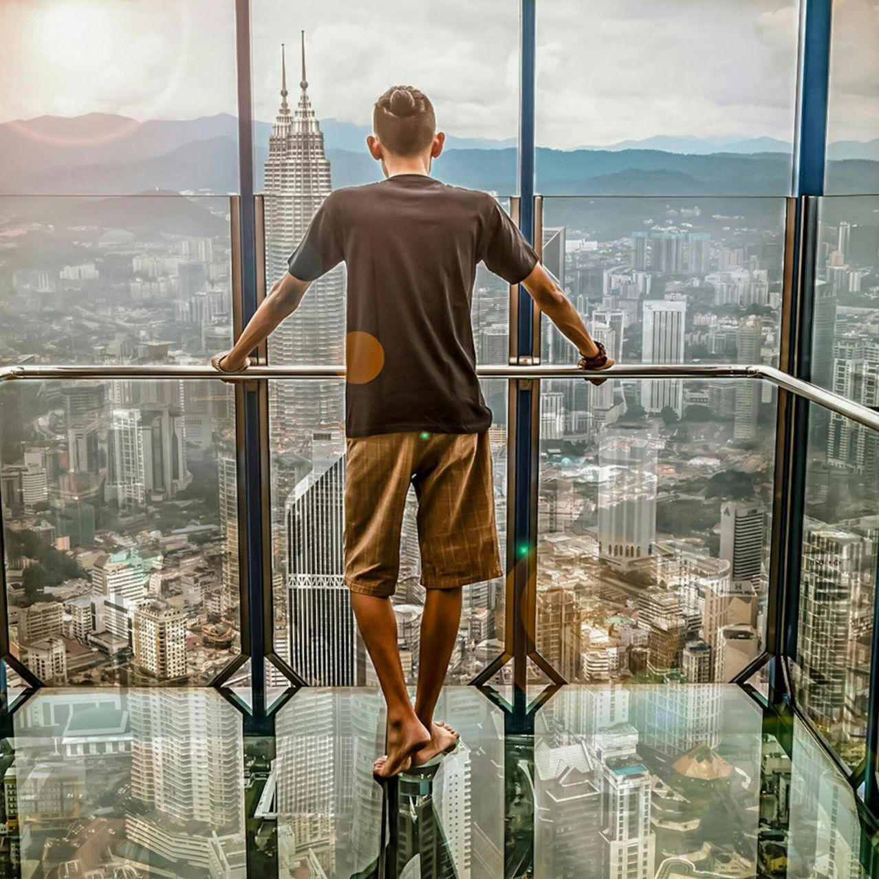 Read Full Letter of Comment Man looking at cityscape from high rise. City with skyscrapers, mountains in distance.
