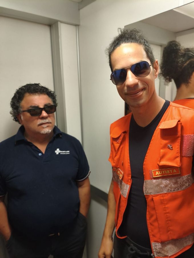 Due paramedici in tuta rossa prestano soccorso a un'anziana signora accanto a un'ambulanza bianca della SOS.