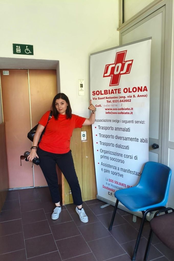 Soccorritori in divisa rossa parlano accanto a un'ambulanza SOS all'aperto.