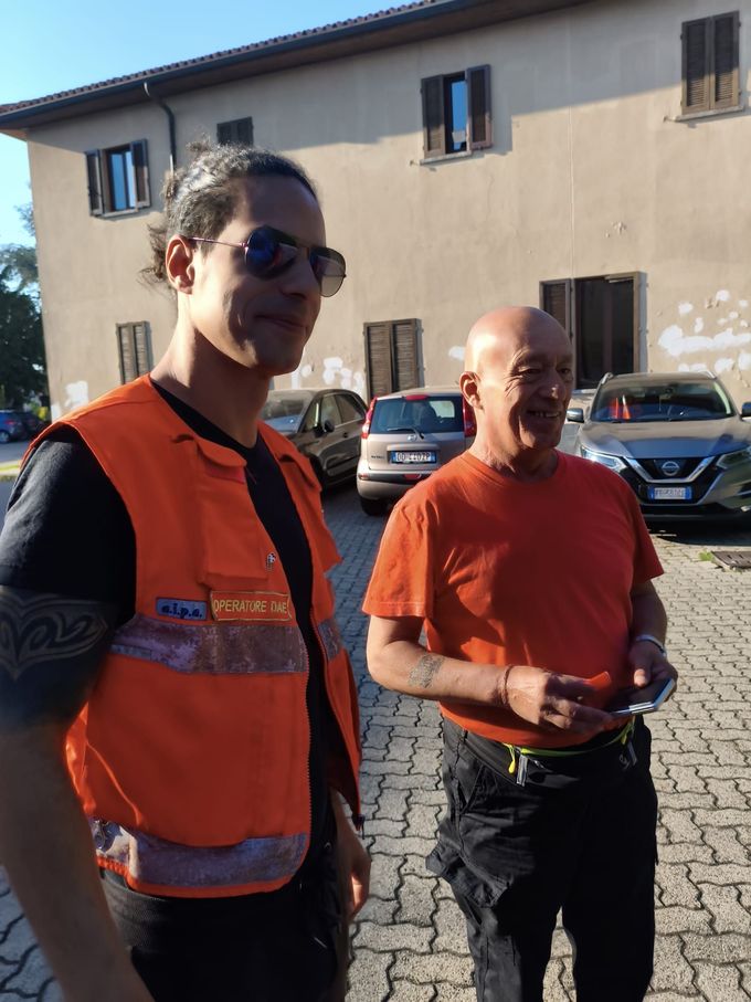 Lezione di primo soccorso: l'istruttore in rosso dimostra la rianimazione cardiopolmonare (RCP) su un manichino ai partecipanti seduti in una stanza luminosa.