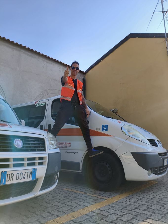 Corso di primo soccorso con istruttore che dimostra la rianimazione cardiopolmonare (RCP) su un manichino, diapositiva sullo sfondo con la scritta