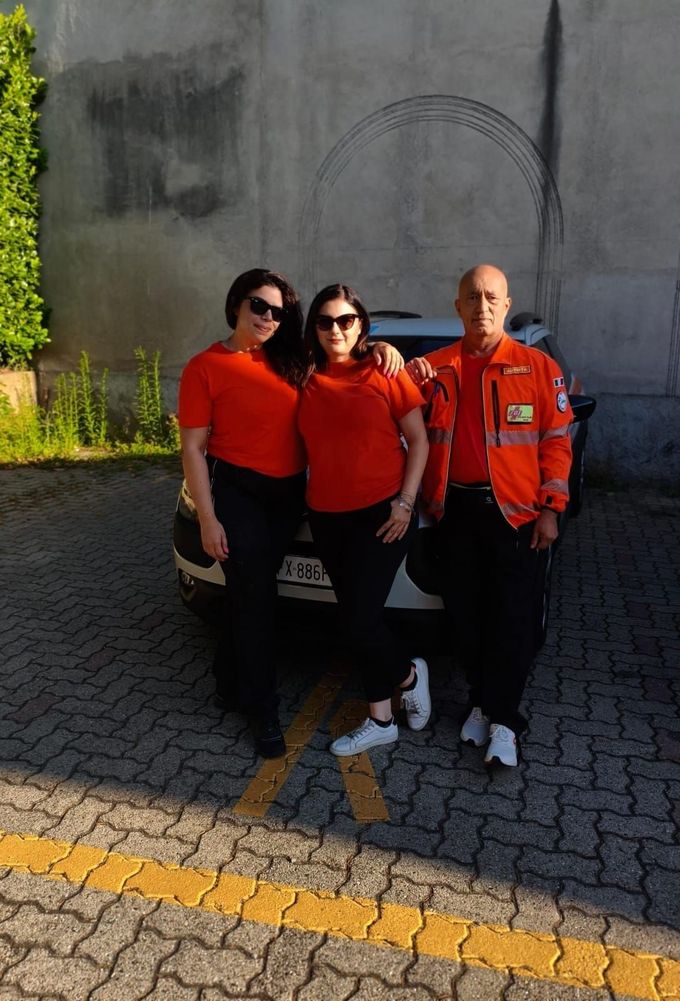 Due persone che camminano insieme fuori da un edificio, una in camice blu, tenendosi per mano