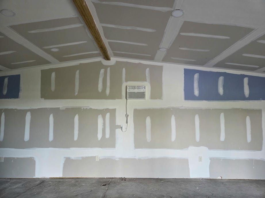 Unfinished garage interior with drywall patches and taped seams on the walls and ceiling