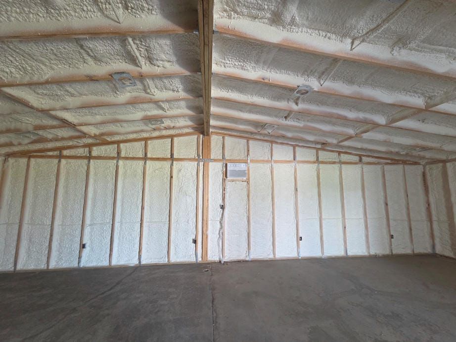 Empty insulated warehouse interior with white spray foam walls and arched ceiling
