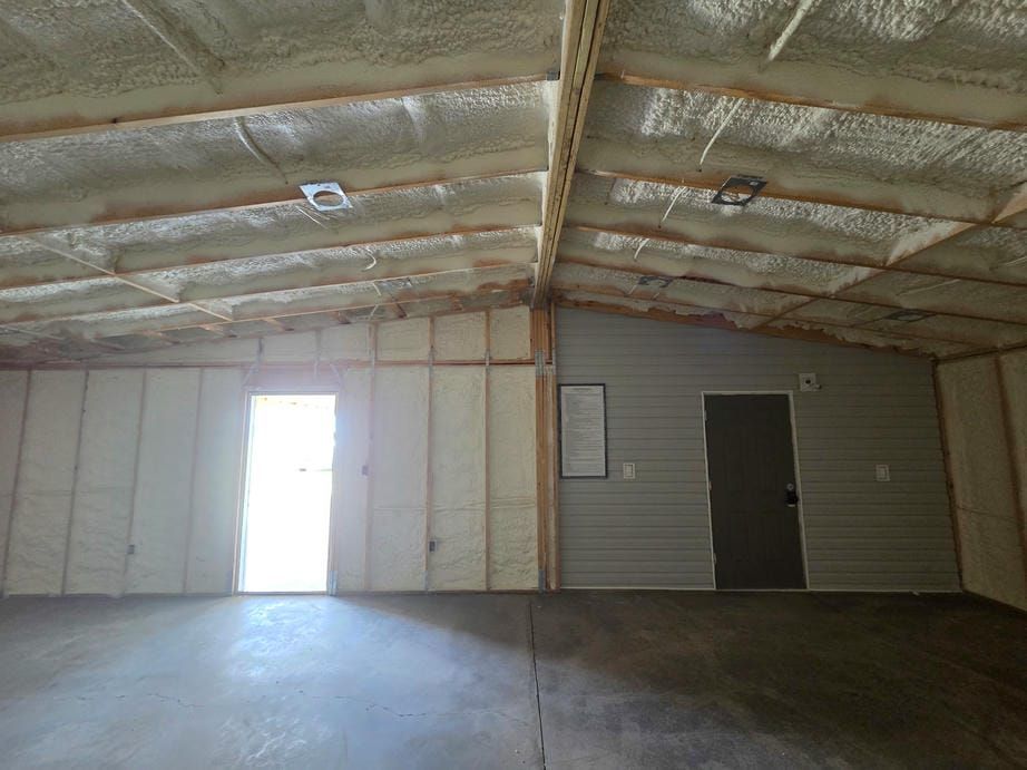 Empty warehouse interior with insulated walls, concrete floor, and two doors at the far end