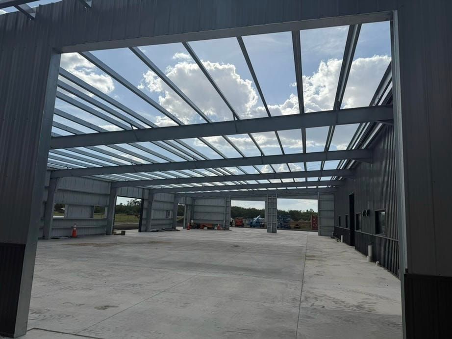 Large open steel-frame warehouse under construction with concrete floor and skylight roof panels
